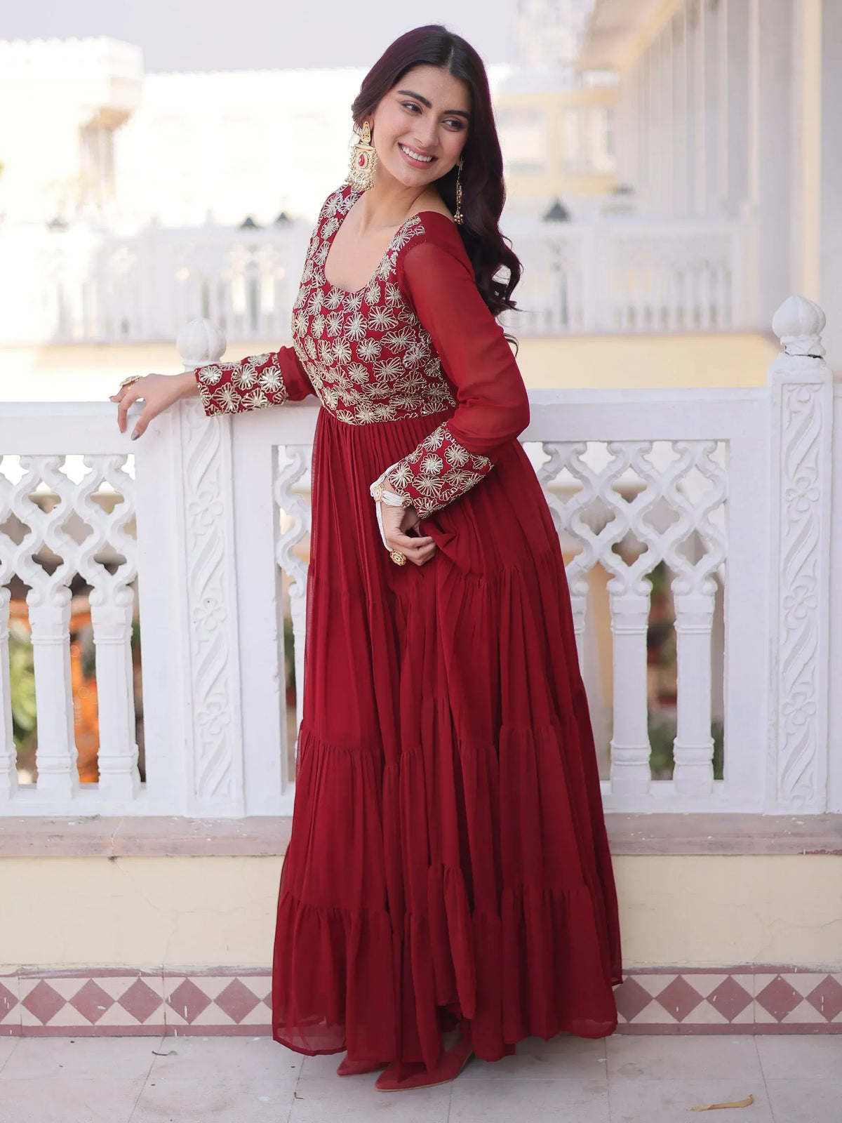 Woman wearing a maroon embroidered ethnic gown with gold detailing