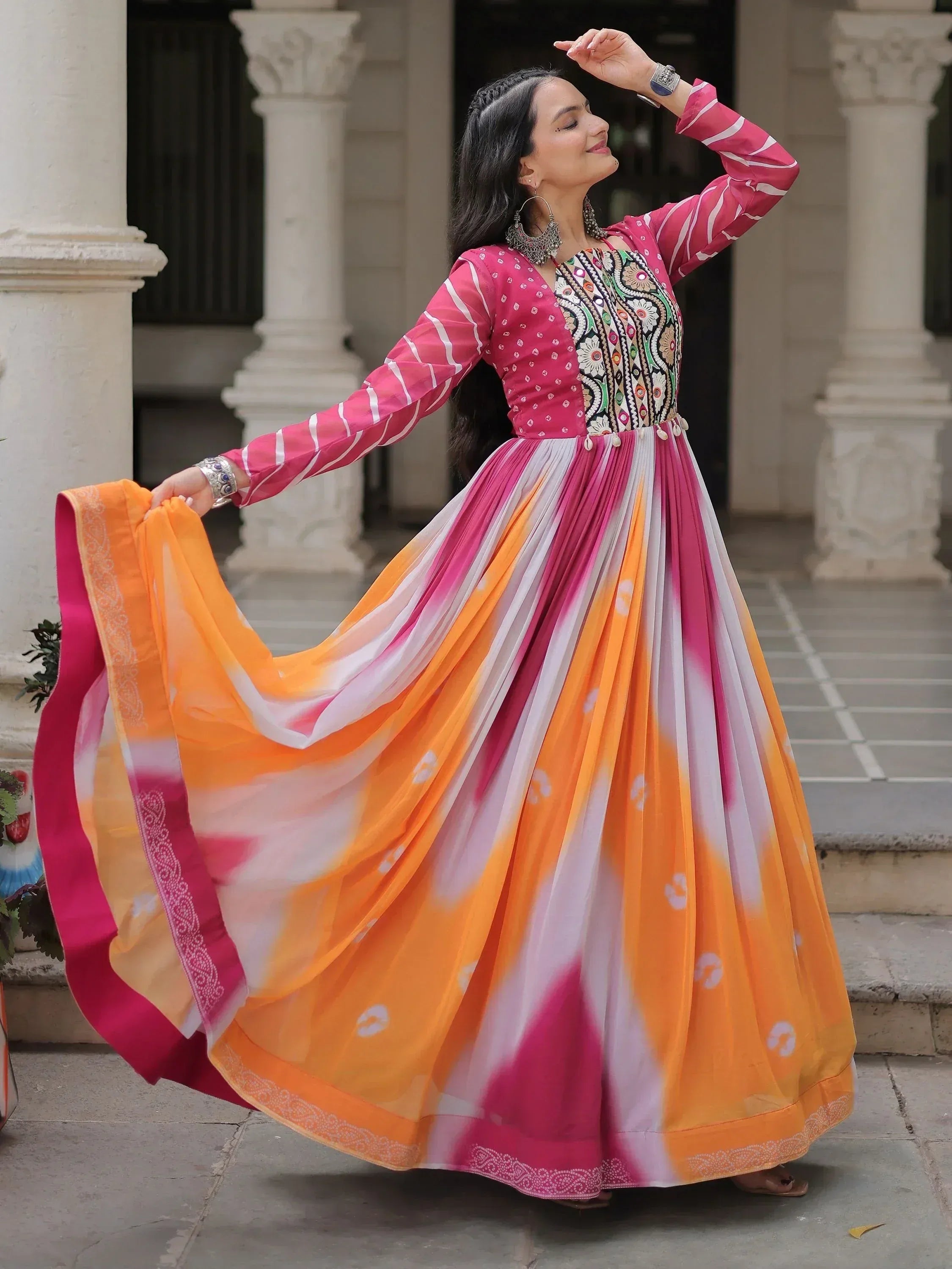 Woman in vibrant pink and orange tie-dye ethnic gown with embroidered top, perfect for festive occasions.