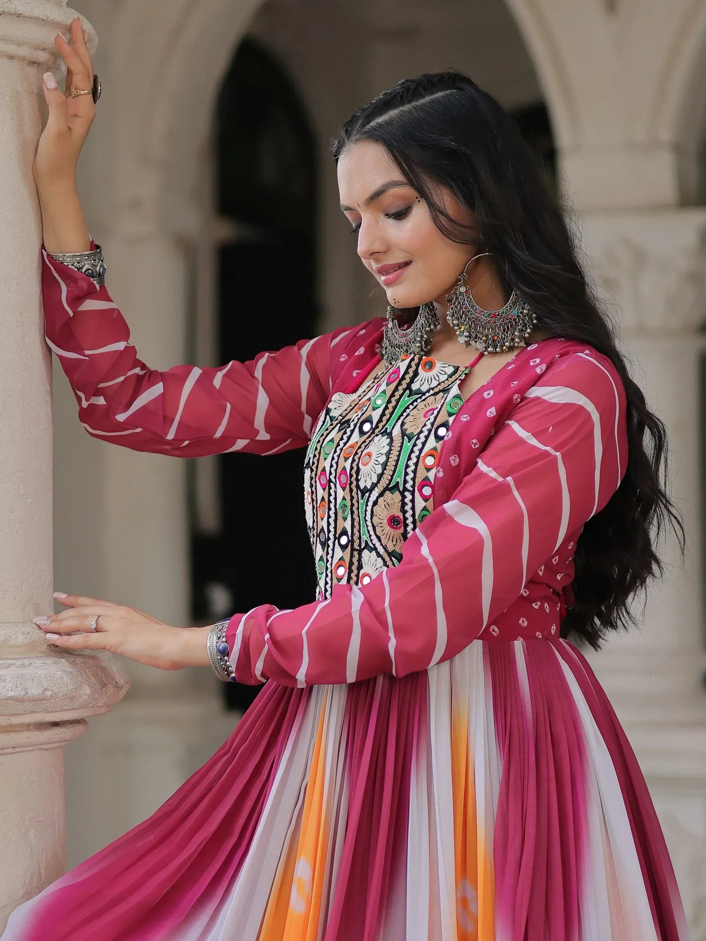 Woman in vibrant pink and white striped ethnic gown with mirror work, styled with traditional jewelry