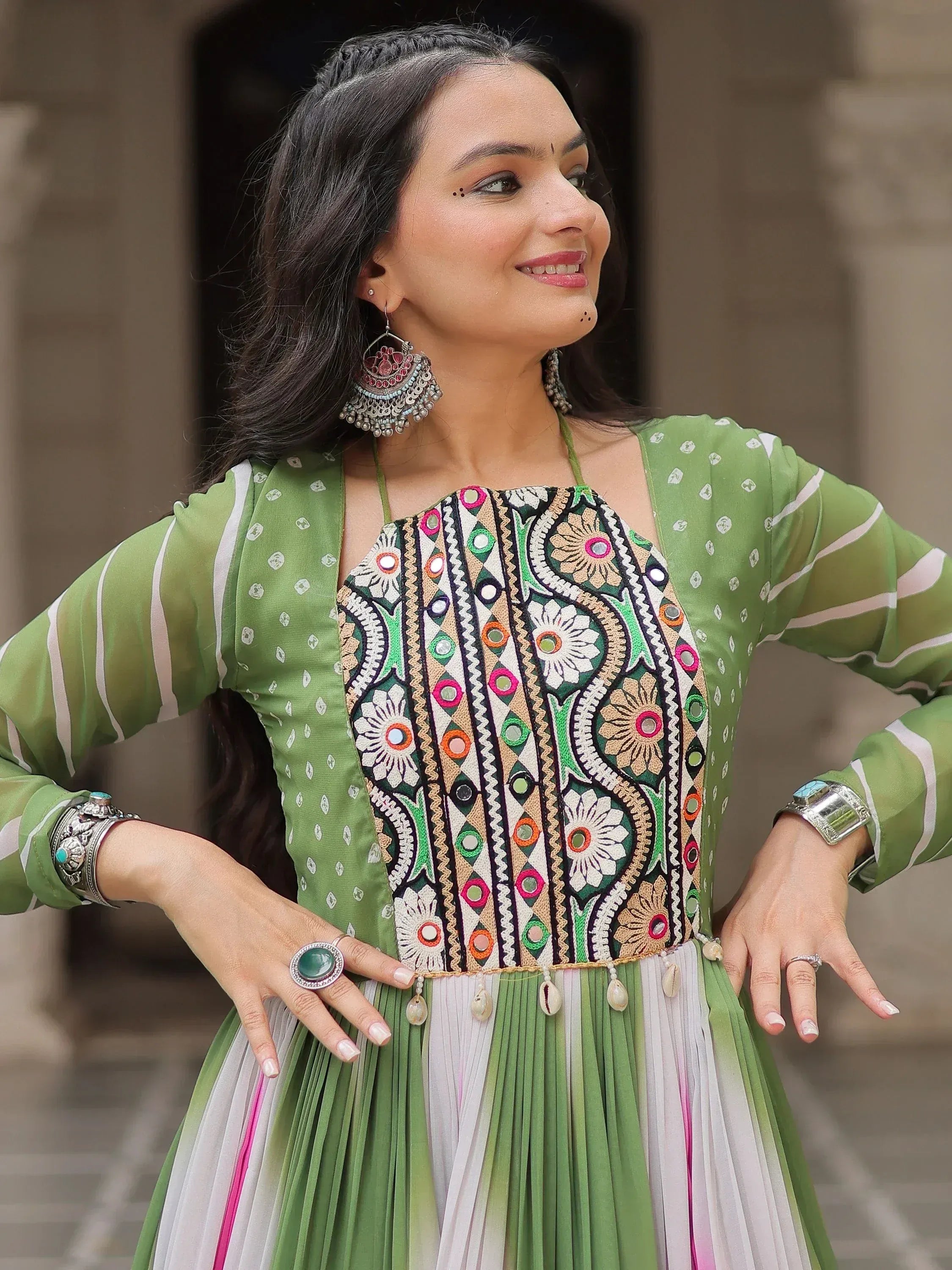Woman in green embroidered ethnic gown with mirror work, floral patterns, and traditional jewelry