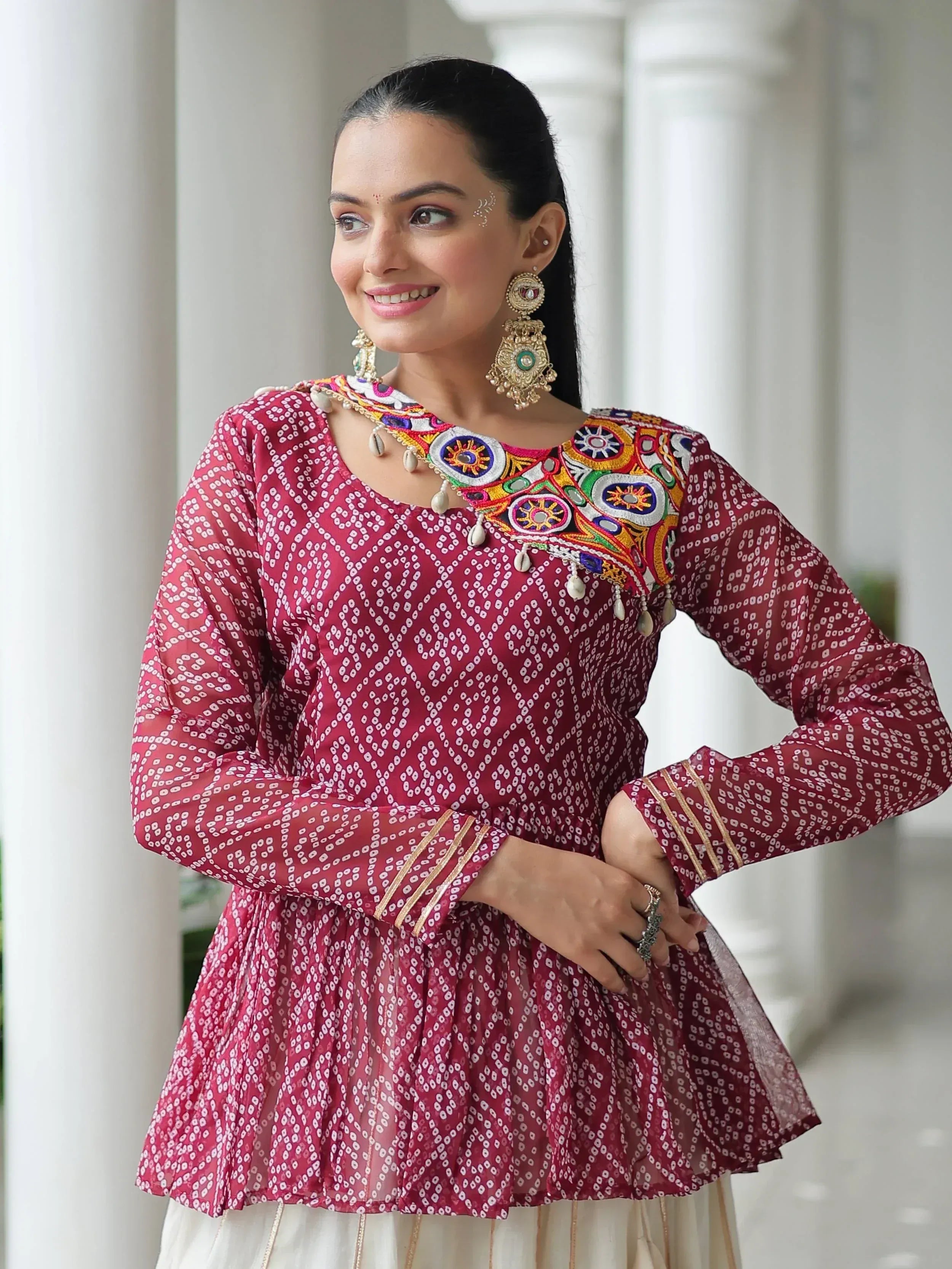 Maroon ethnic kurta with colorful mirror embroidery and white pattern, paired with traditional jewelry