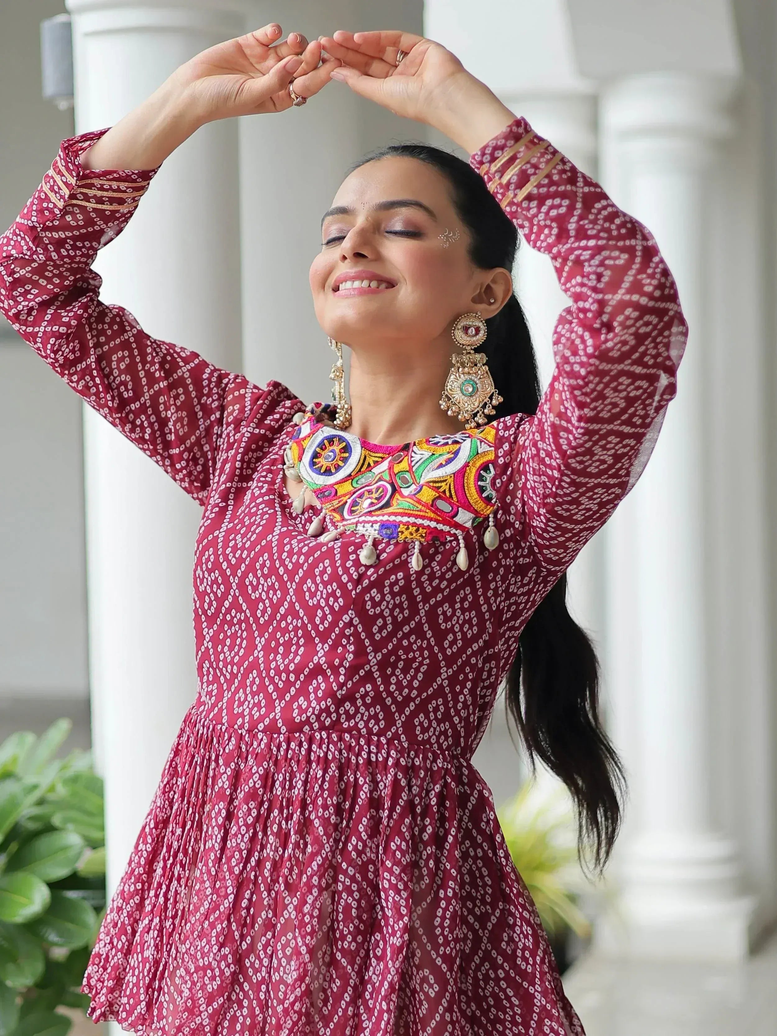 Woman in maroon printed ethnic gown with colorful embroidery, perfect for Indian festive occasions.