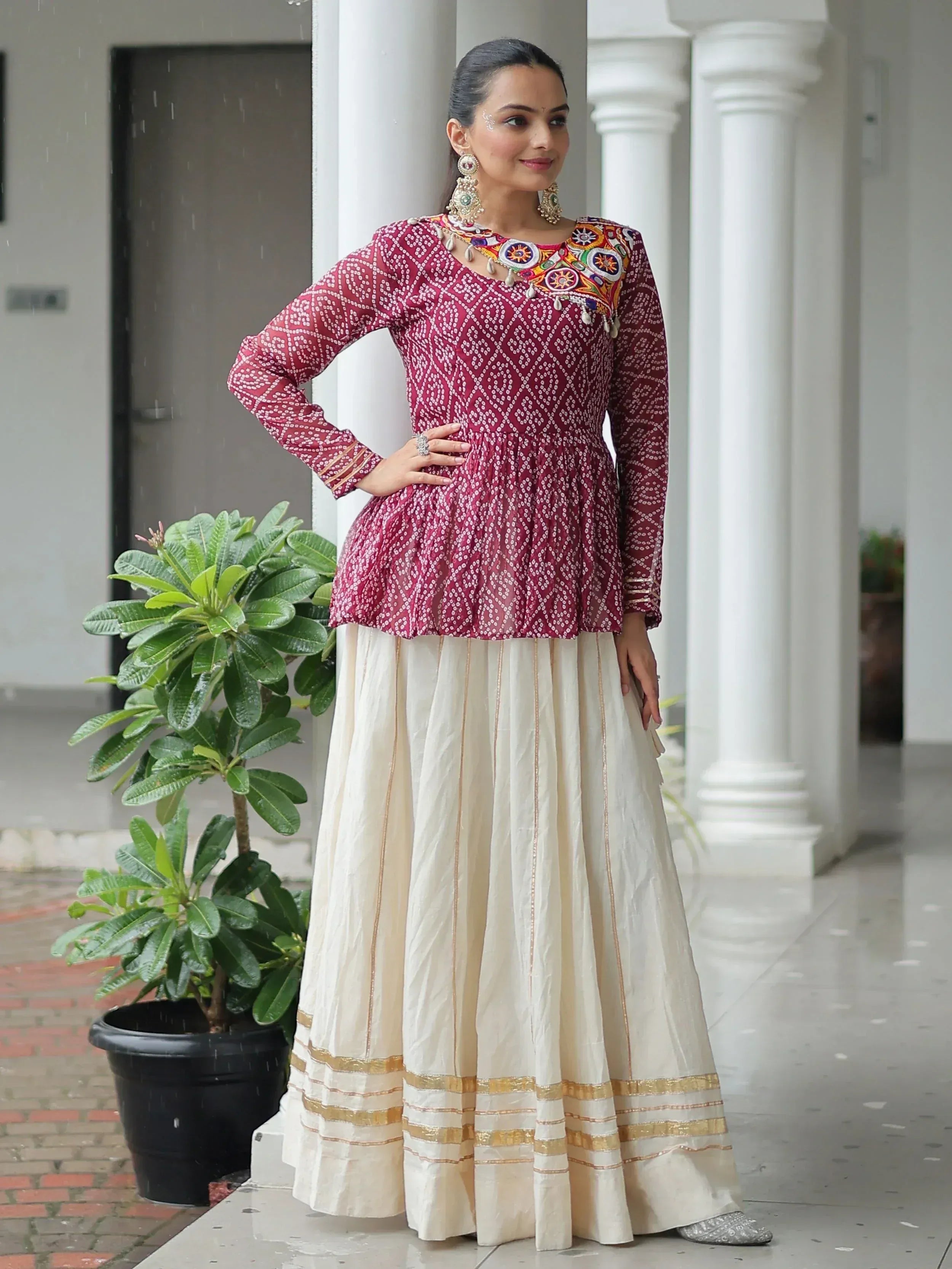 Woman in maroon embroidered kurta with cream pleated skirt, ethnic Indian wear for festive occasions