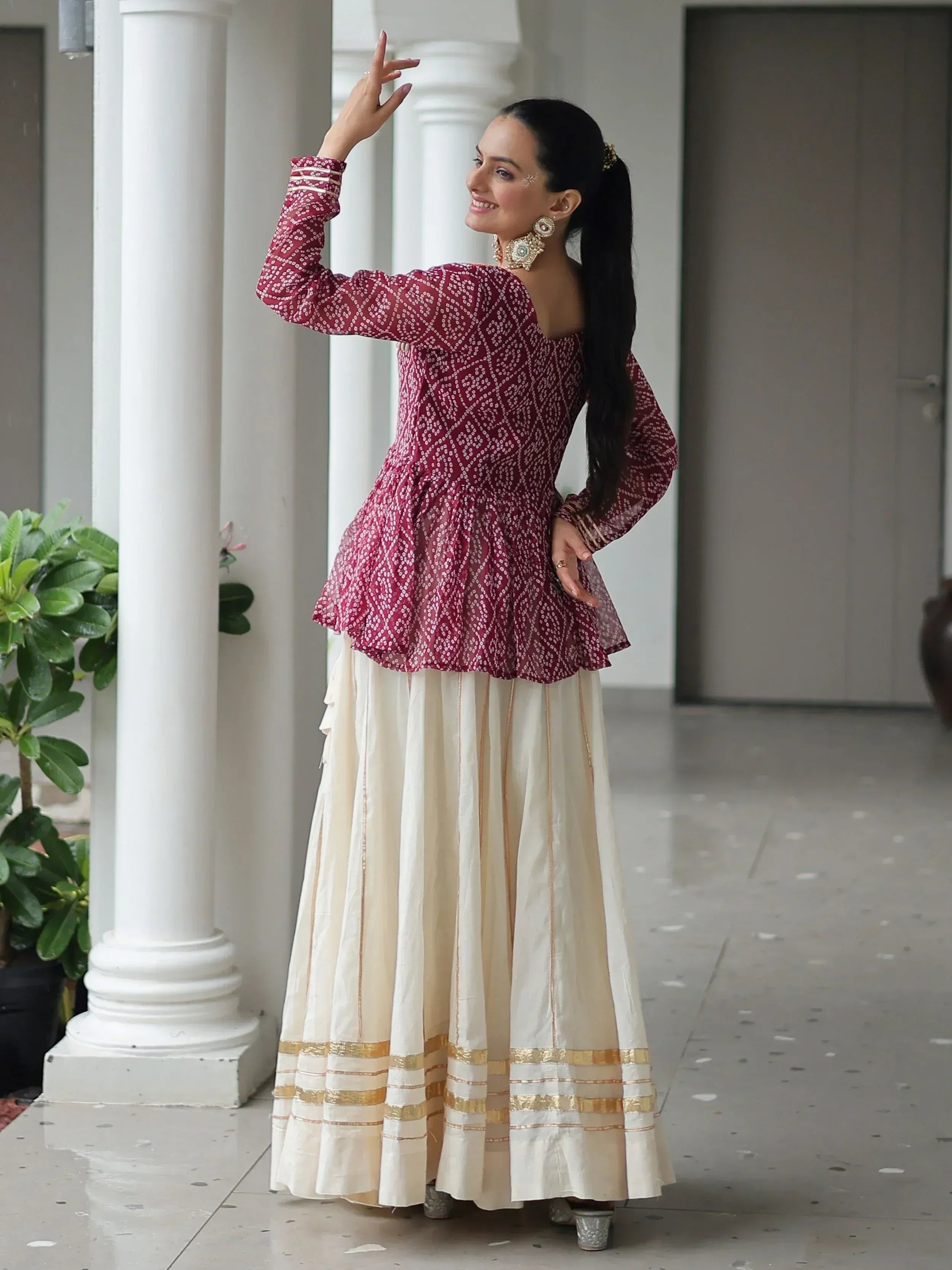 Woman in maroon printed peplum top and cream skirt with gold trim, Indian ethnic wear