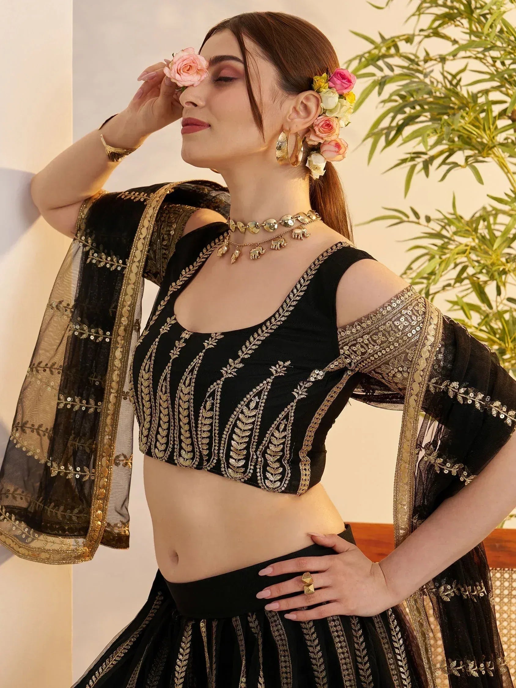 Black and gold embroidered lehenga choli with floral hair accessories, perfect for Indian ethnic wear.