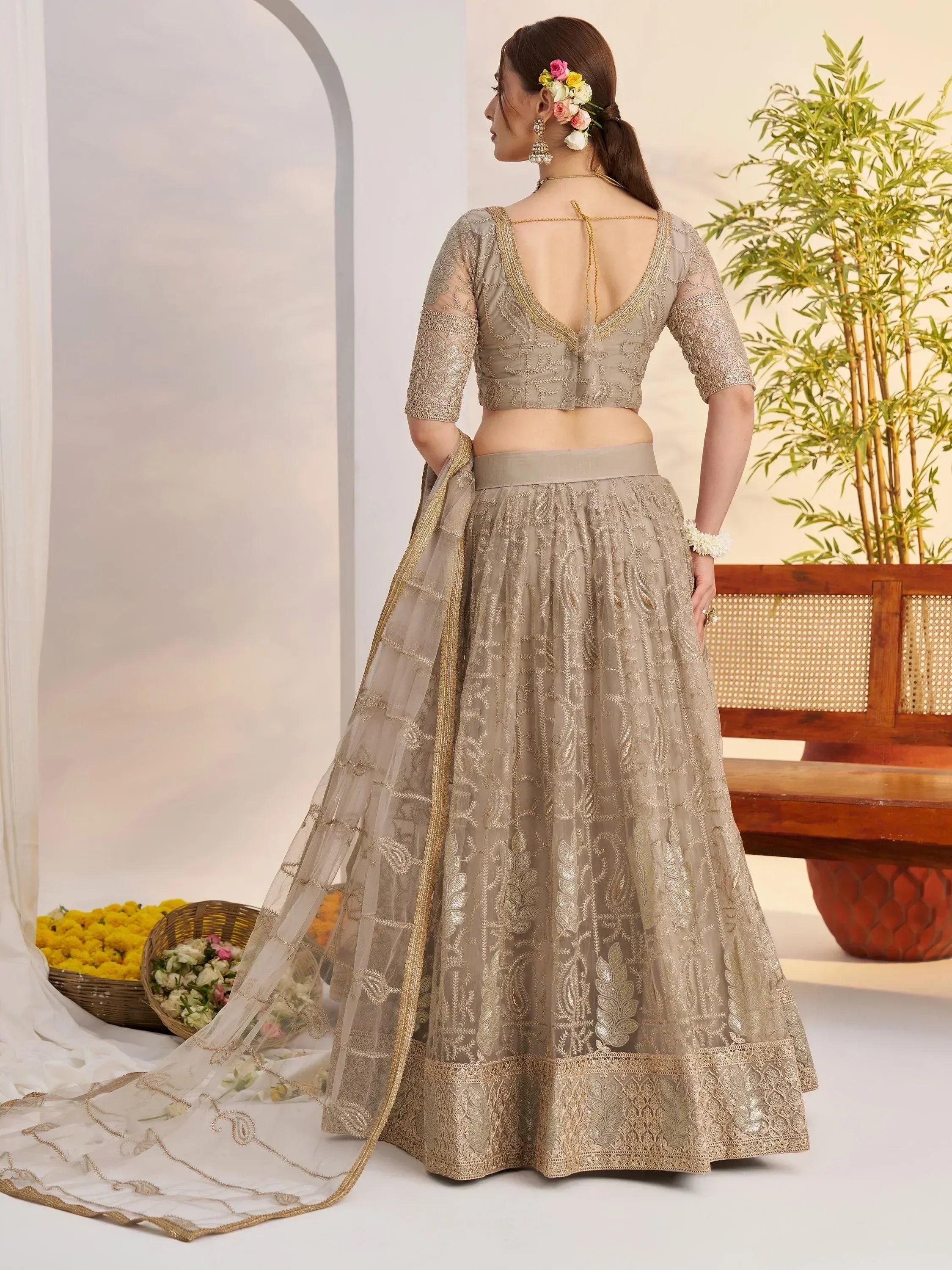 Elegant beige embroidered lehenga choli with open back blouse and floral hair accessory