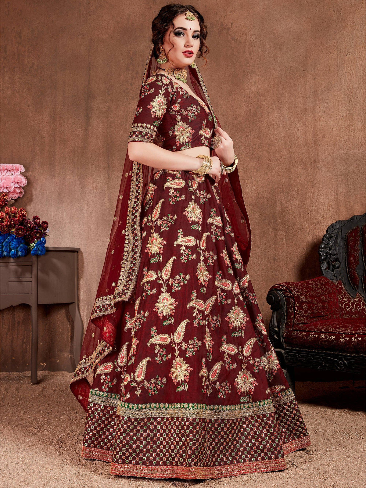 Maroon embroidered lehenga choli with floral and paisley motifs, perfect for Indian weddings and festive occasions.