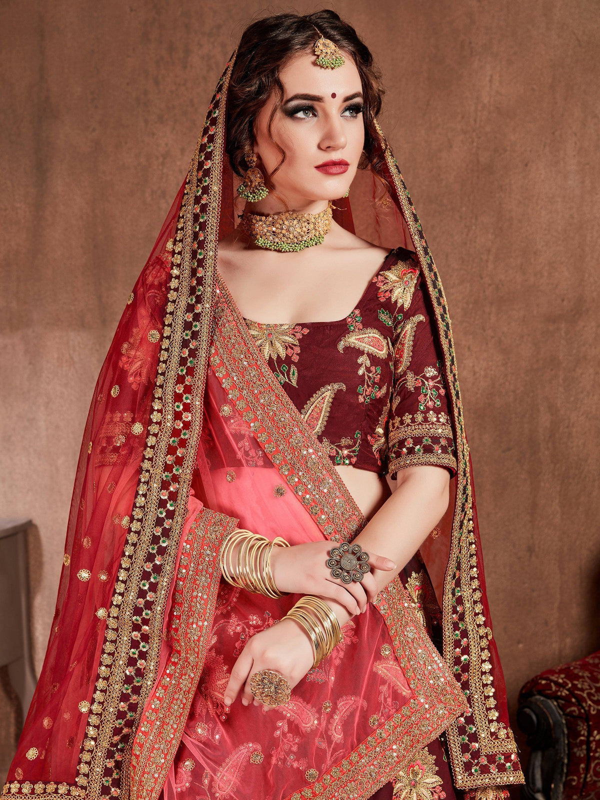 Maroon and red embroidered lehenga choli with gold detailing, perfect for Indian weddings and festive occasions.