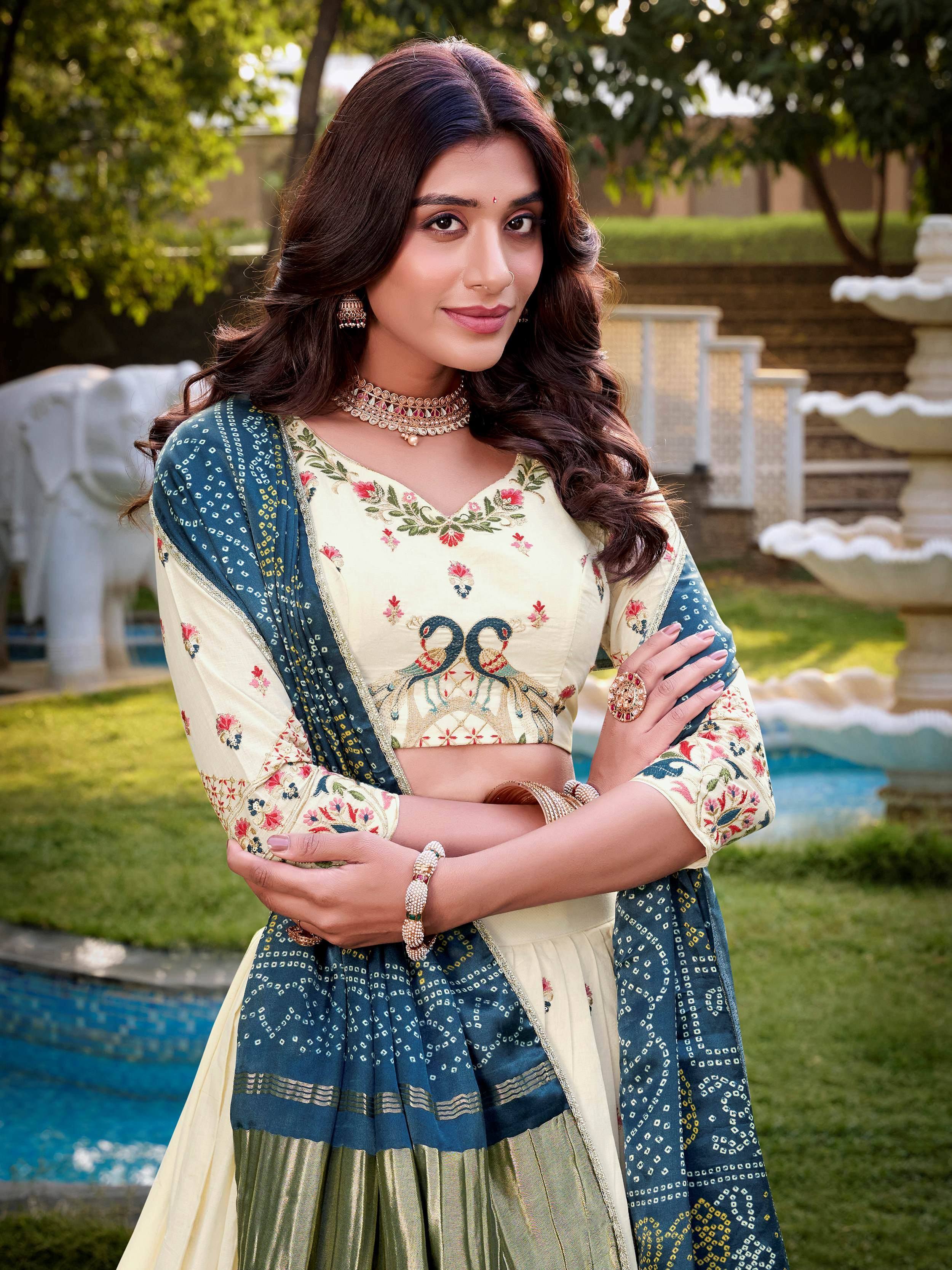 Woman in cream and blue embroidered lehenga choli with peacock design, garden setting
