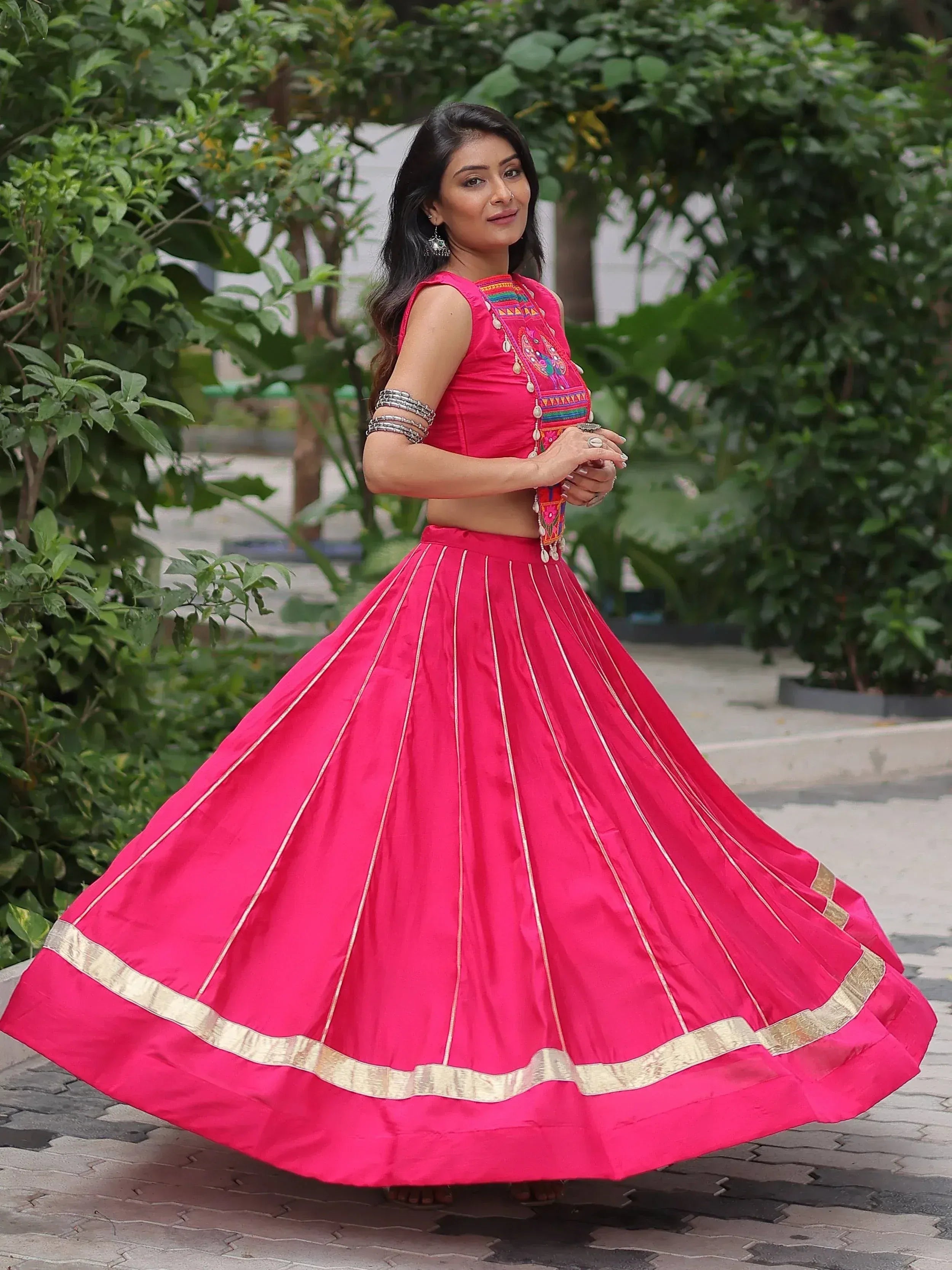 Woman in vibrant pink embroidered lehenga choli with gold trim, perfect for Indian ethnic wear occasions