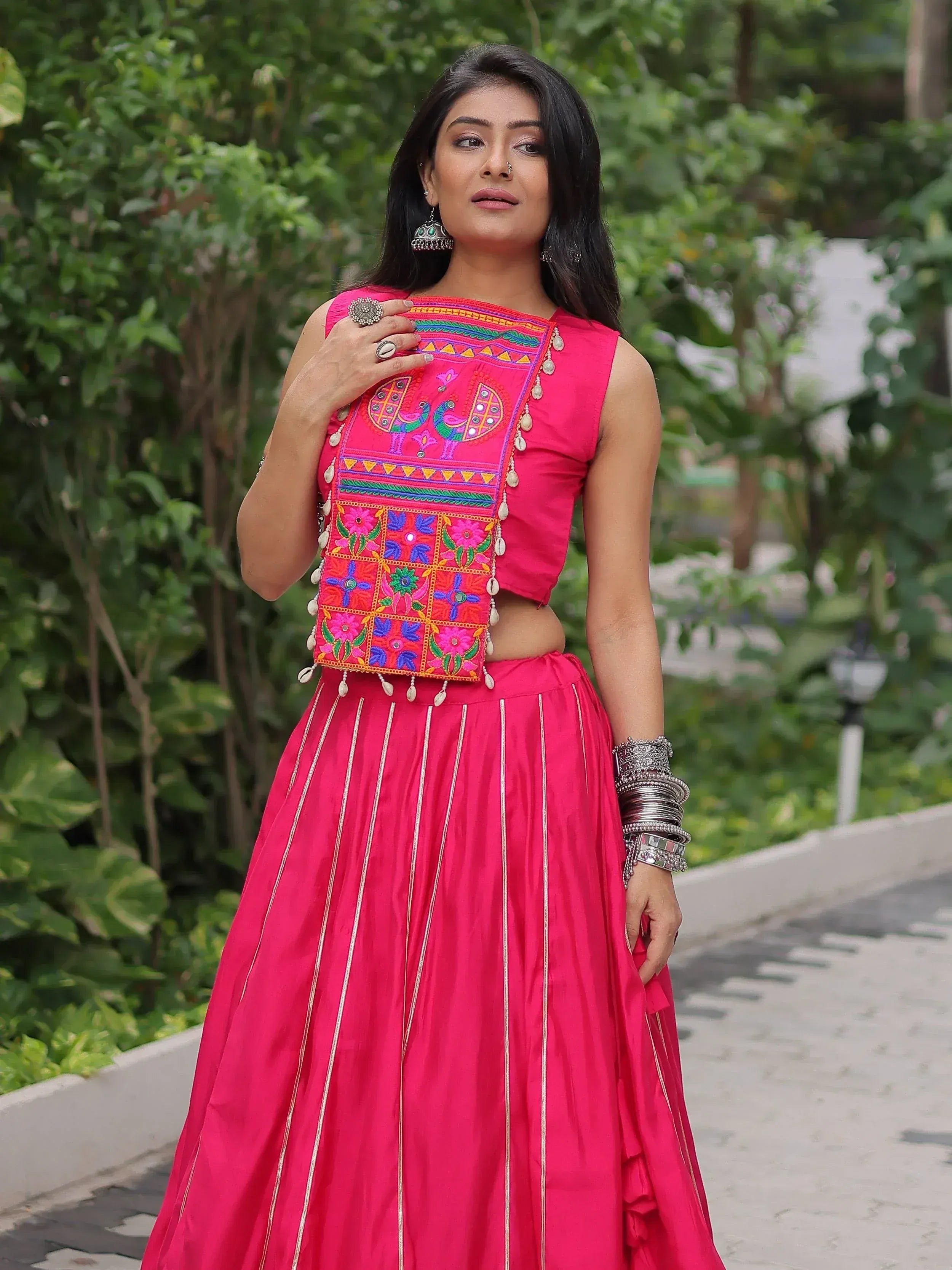 Pink embroidered lehenga choli with mirror work, floral motifs, and silver detailing, styled with traditional jewelry