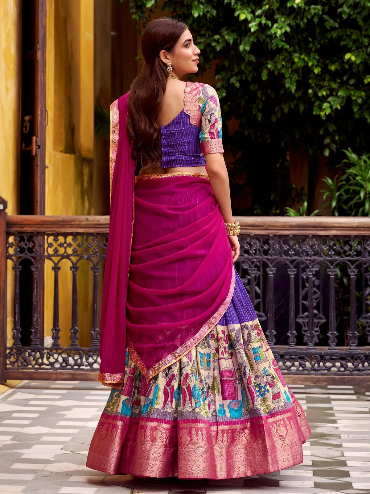 Woman in vibrant purple and magenta lehenga choli with printed motifs, perfect for Indian ethnic wear occasions.