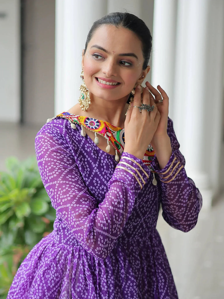 Woman in purple ethnic gown with colorful embroidery and traditional jewelry, perfect for festive occasions.