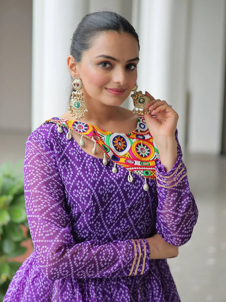 Purple ethnic gown with colorful embroidery and mirror work, paired with traditional jhumka earrings