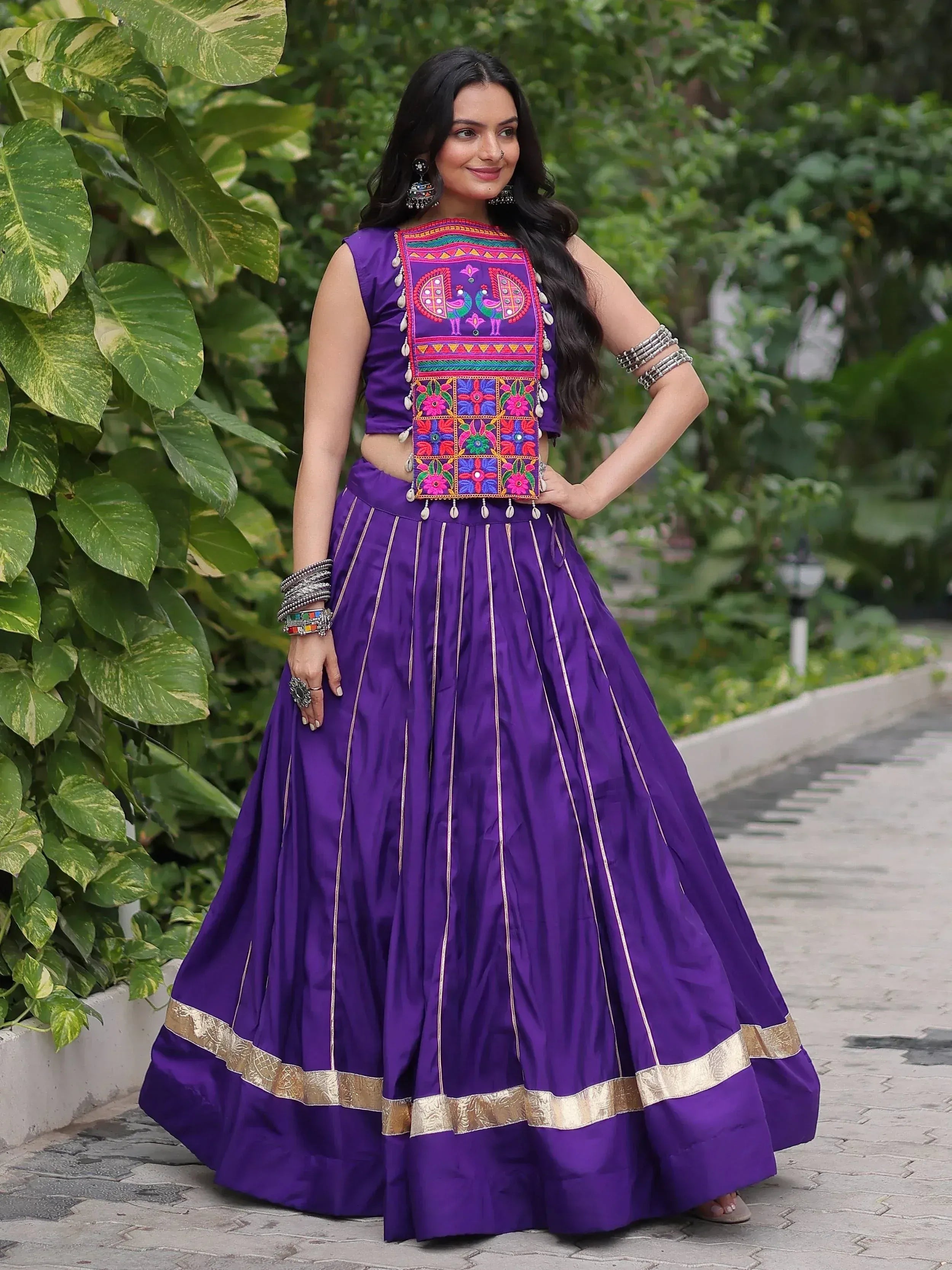 Purple embroidered lehenga choli with peacock motifs, gold trim, and traditional jewelry for ethnic wear