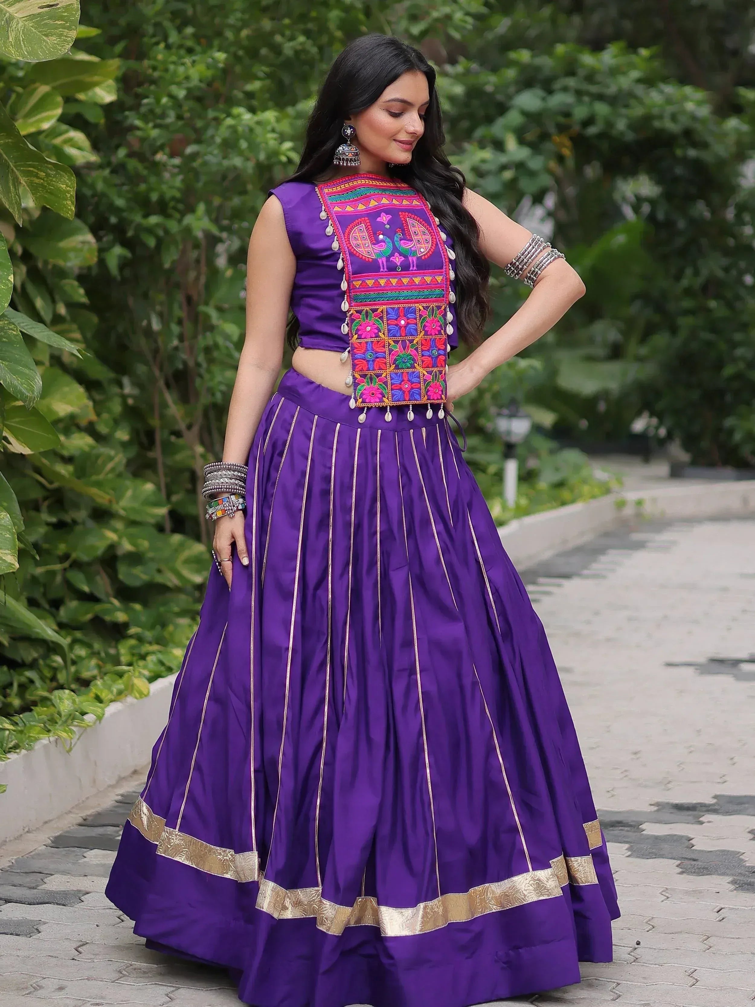 Purple embroidered lehenga choli with peacock motif, gold trim, and traditional Indian jewelry