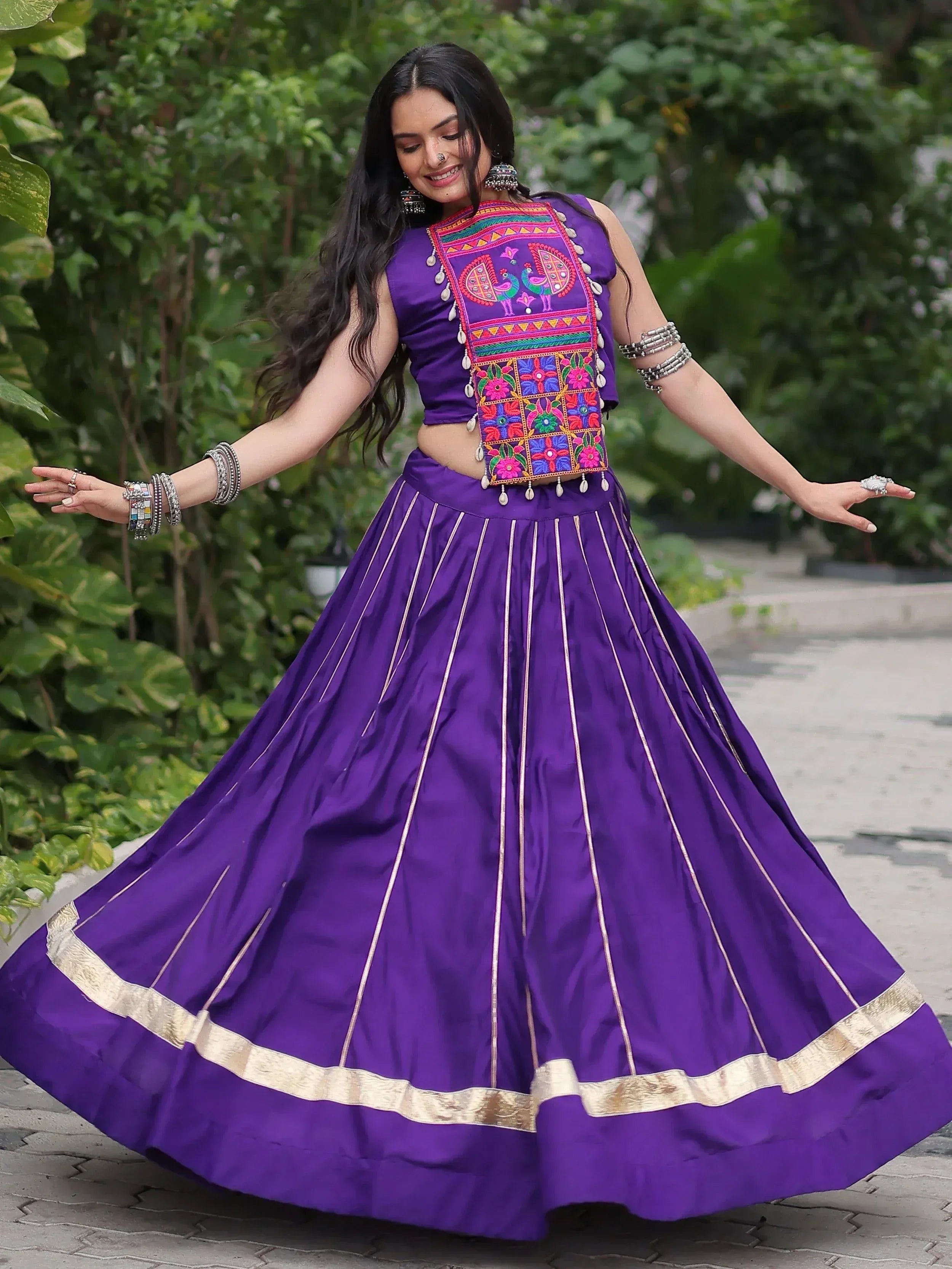 Purple embroidered lehenga choli with peacock motif, gold trim, and silver jewelry for Indian ethnic wear