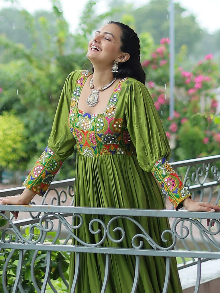 Woman in green embroidered ethnic gown enjoying rain on balcony, floral embroidery, traditional Indian wear