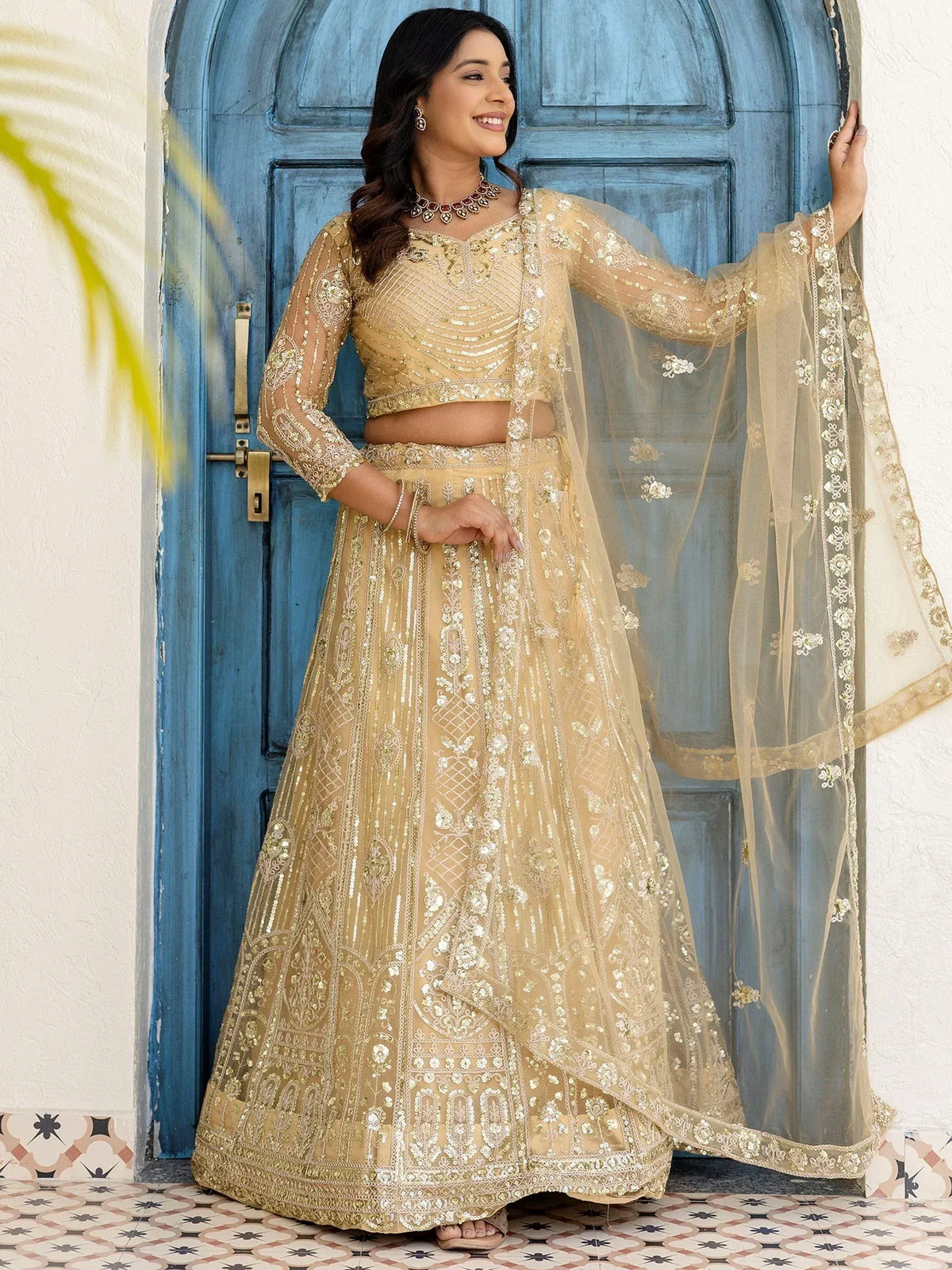 Elegant gold embroidered lehenga choli with sheer dupatta, perfect for Indian weddings and festive occasions.