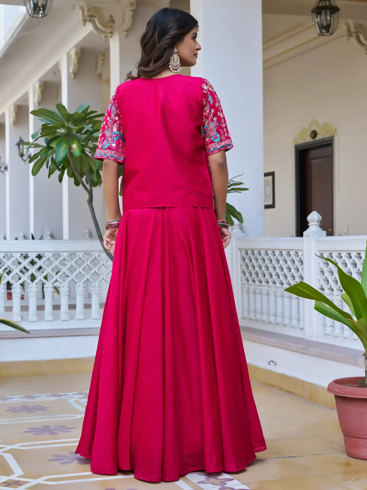Vibrant pink ethnic gown with embroidered sleeves, perfect for Indian occasions and festive wear.