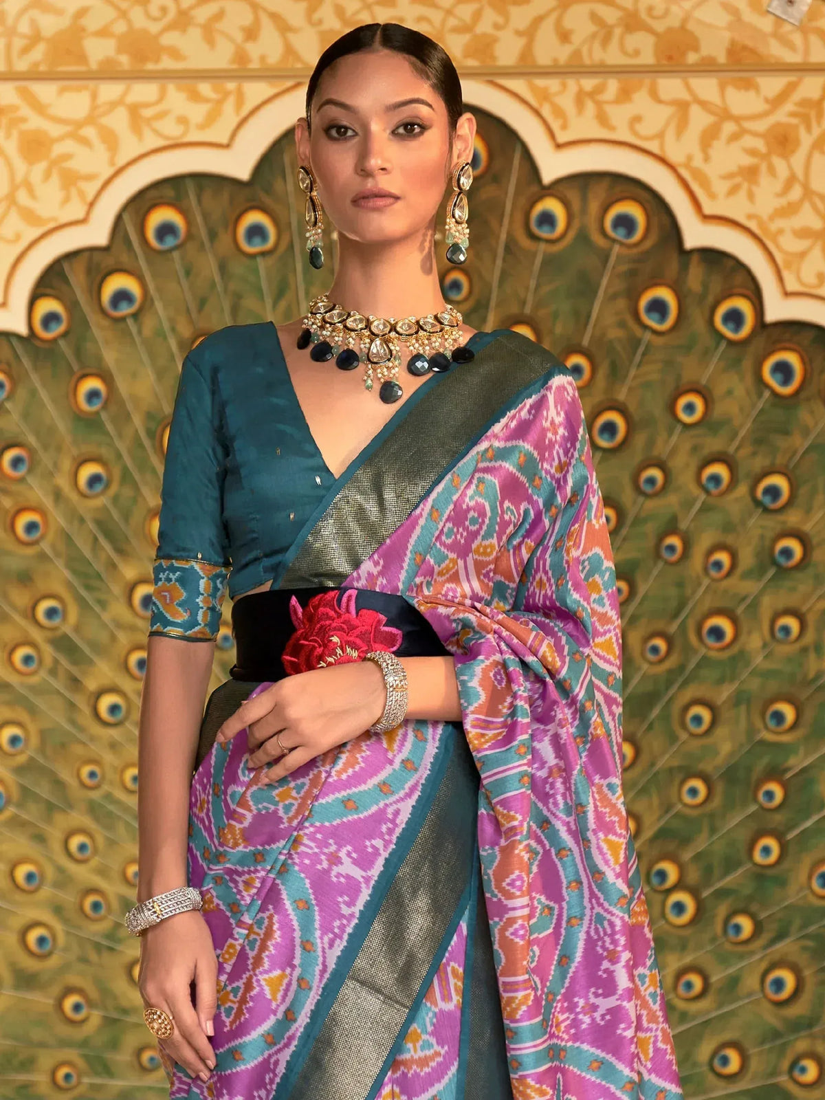 Vibrant pink and teal ikat saree with designer blouse, paired with statement jewelry for ethnic wear.