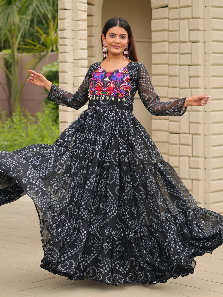 Woman in black ethnic gown with colorful elephant embroidery and sheer sleeves, twirling outdoors