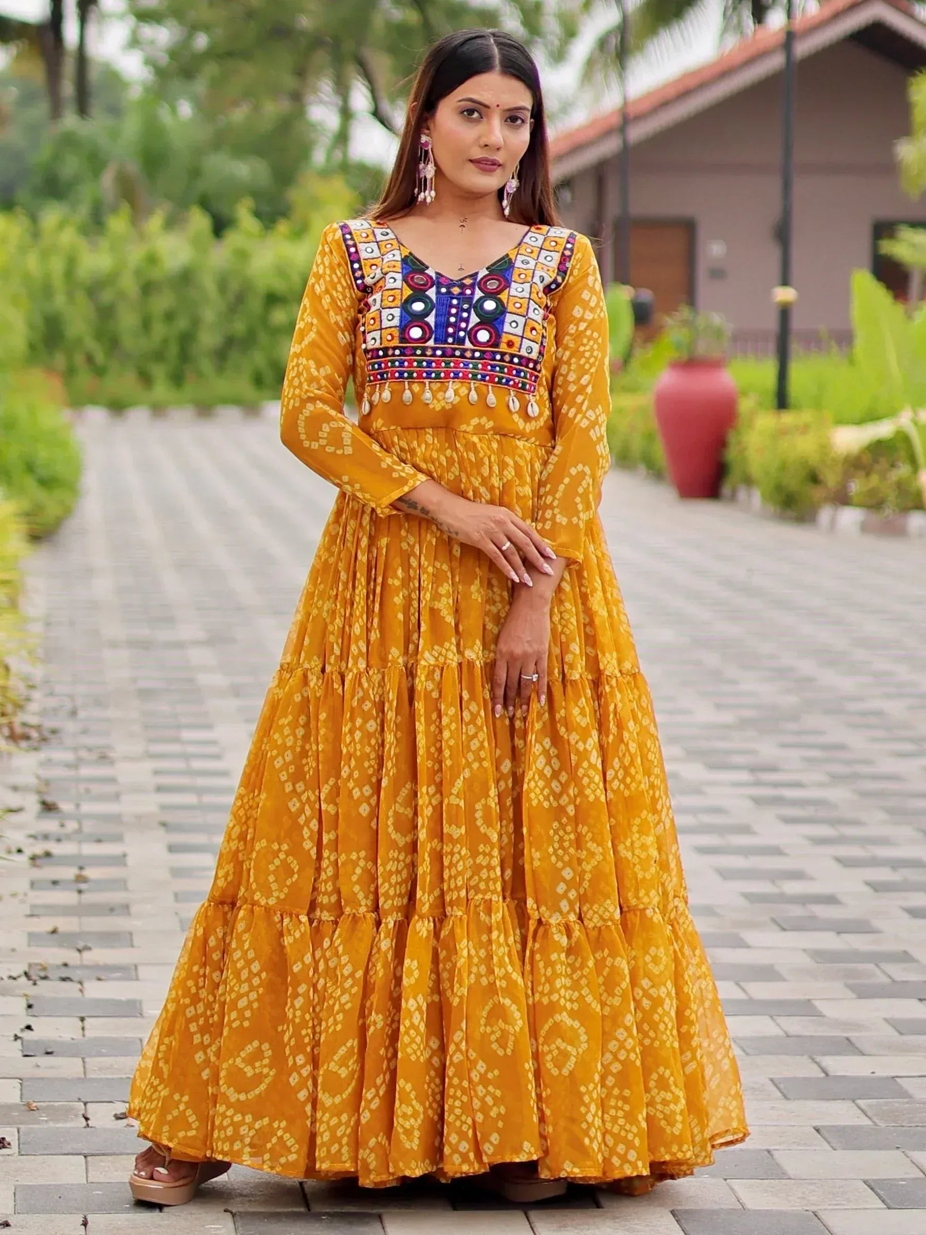 Mustard yellow ethnic gown with mirror work and tiered skirt, perfect for Indian occasions