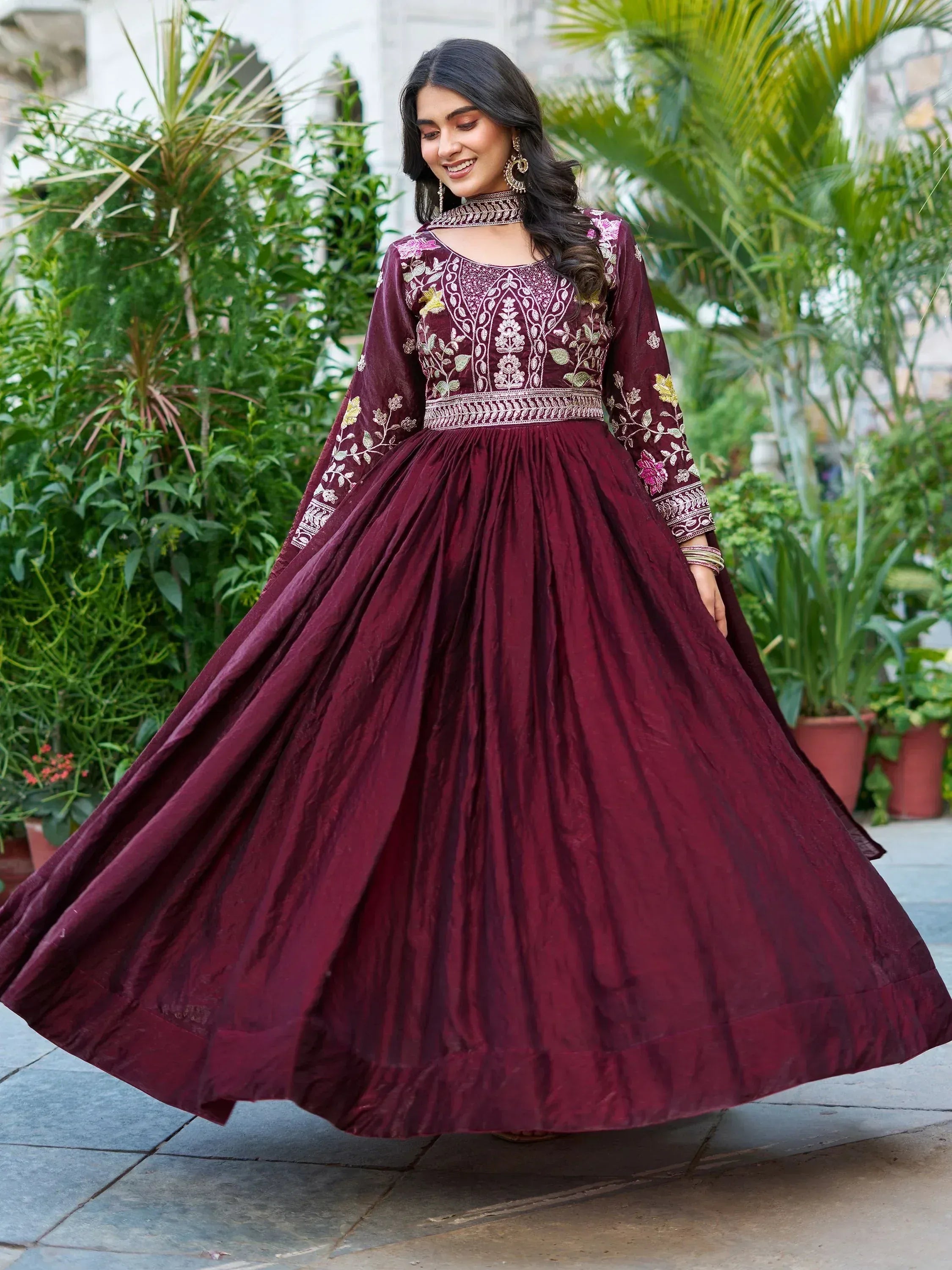Woman in maroon embroidered anarkali gown with floral detailing, perfect for Indian ethnic occasions.