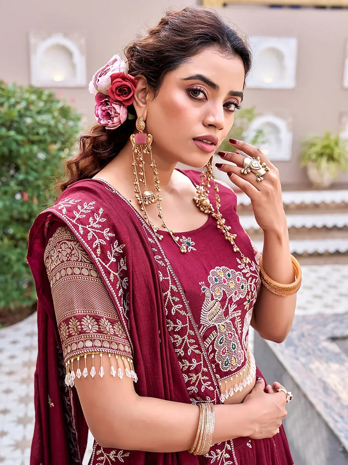 Woman wearing a maroon embroidered Indian ethnic salwar kameez with heavy gold jewelry
