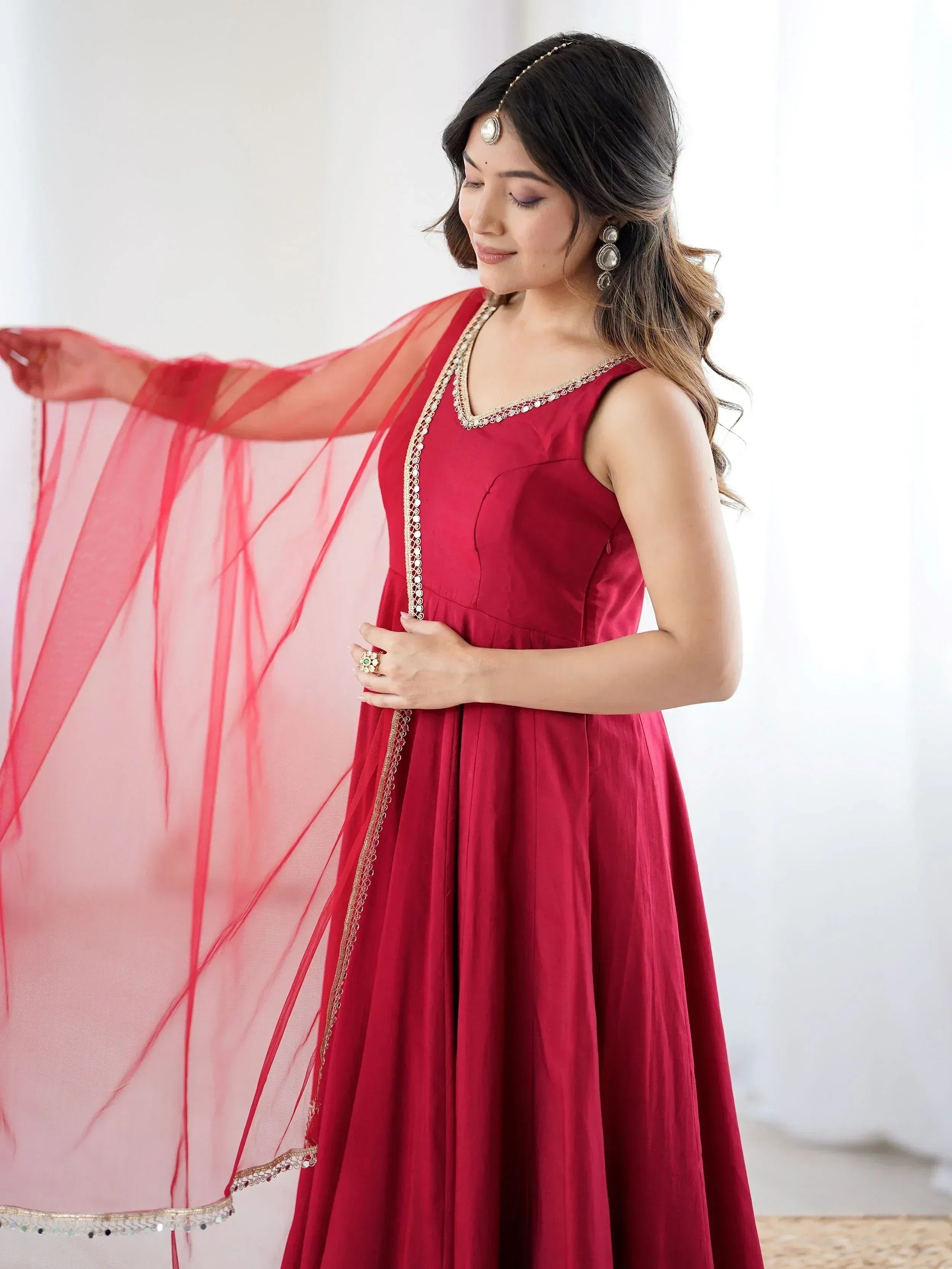Woman in red ethnic gown with gold embroidery and sheer dupatta, perfect for Indian celebrations