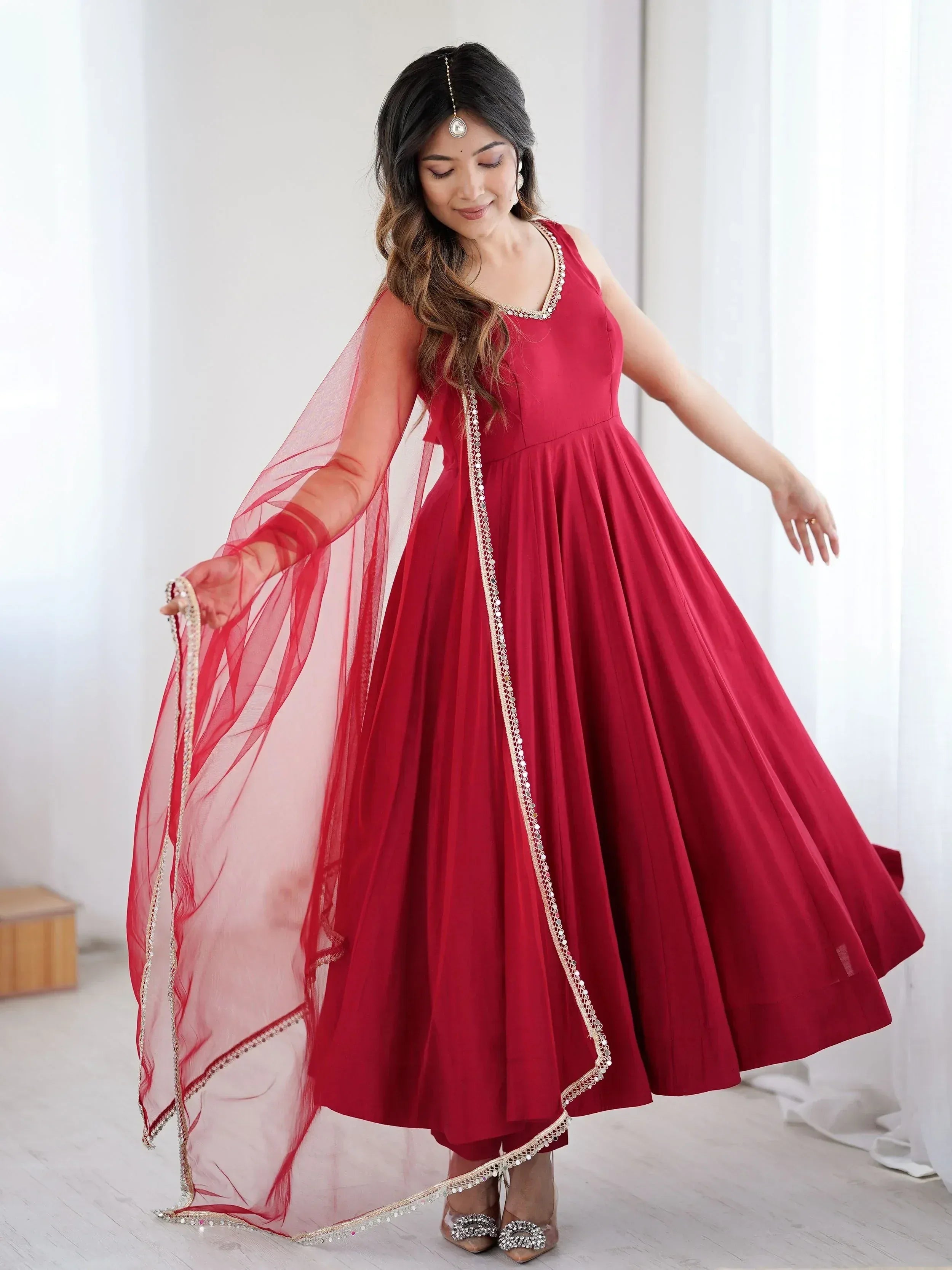 Red ethnic gown with gold embroidery and sheer dupatta, perfect for Indian celebrations