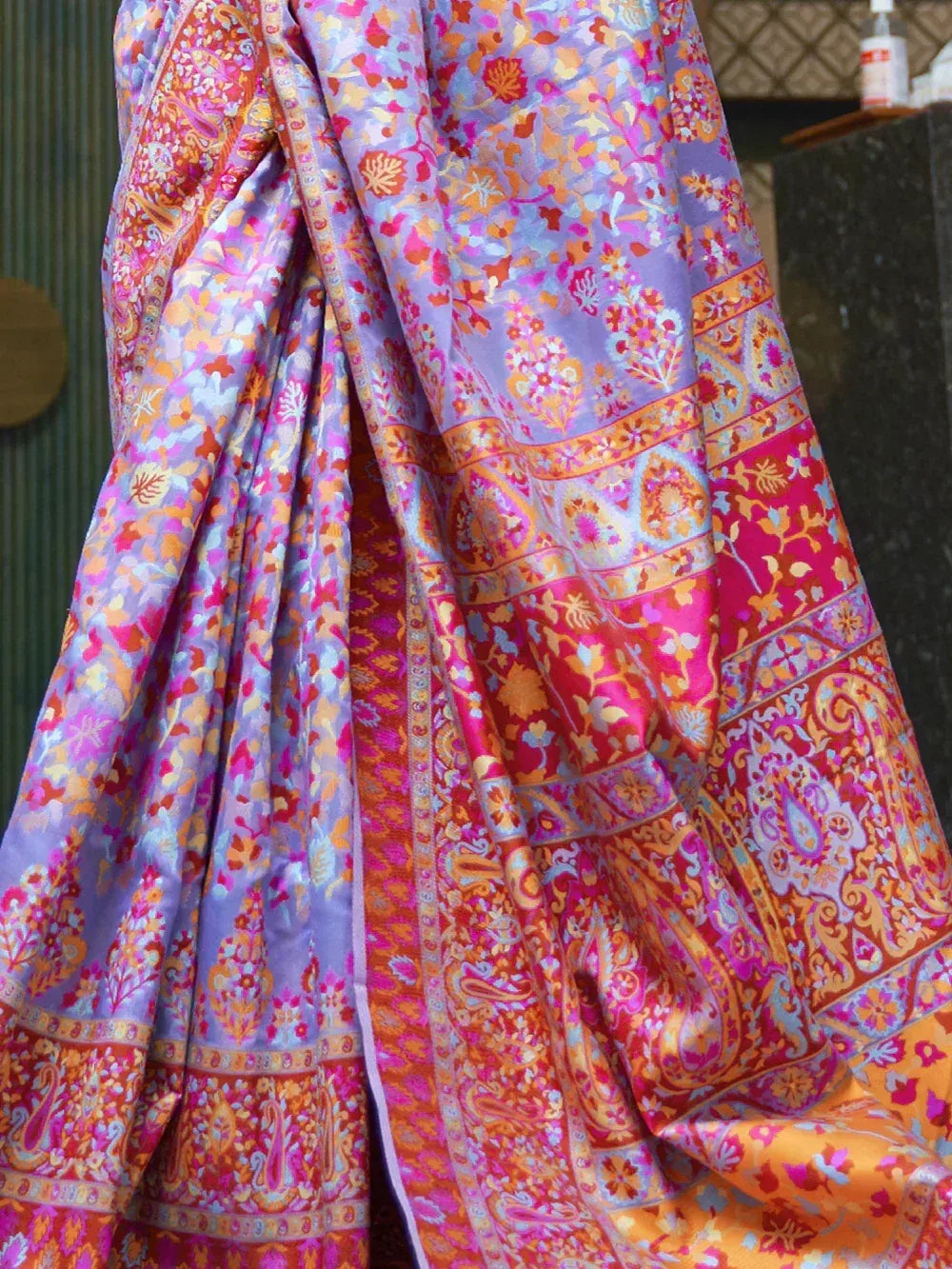 Vibrant floral and paisley printed saree in purple, pink, and orange hues, perfect for ethnic occasions.