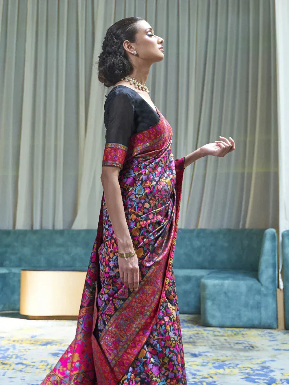 Woman in vibrant floral saree with black blouse, elegant ethnic wear for festive occasions