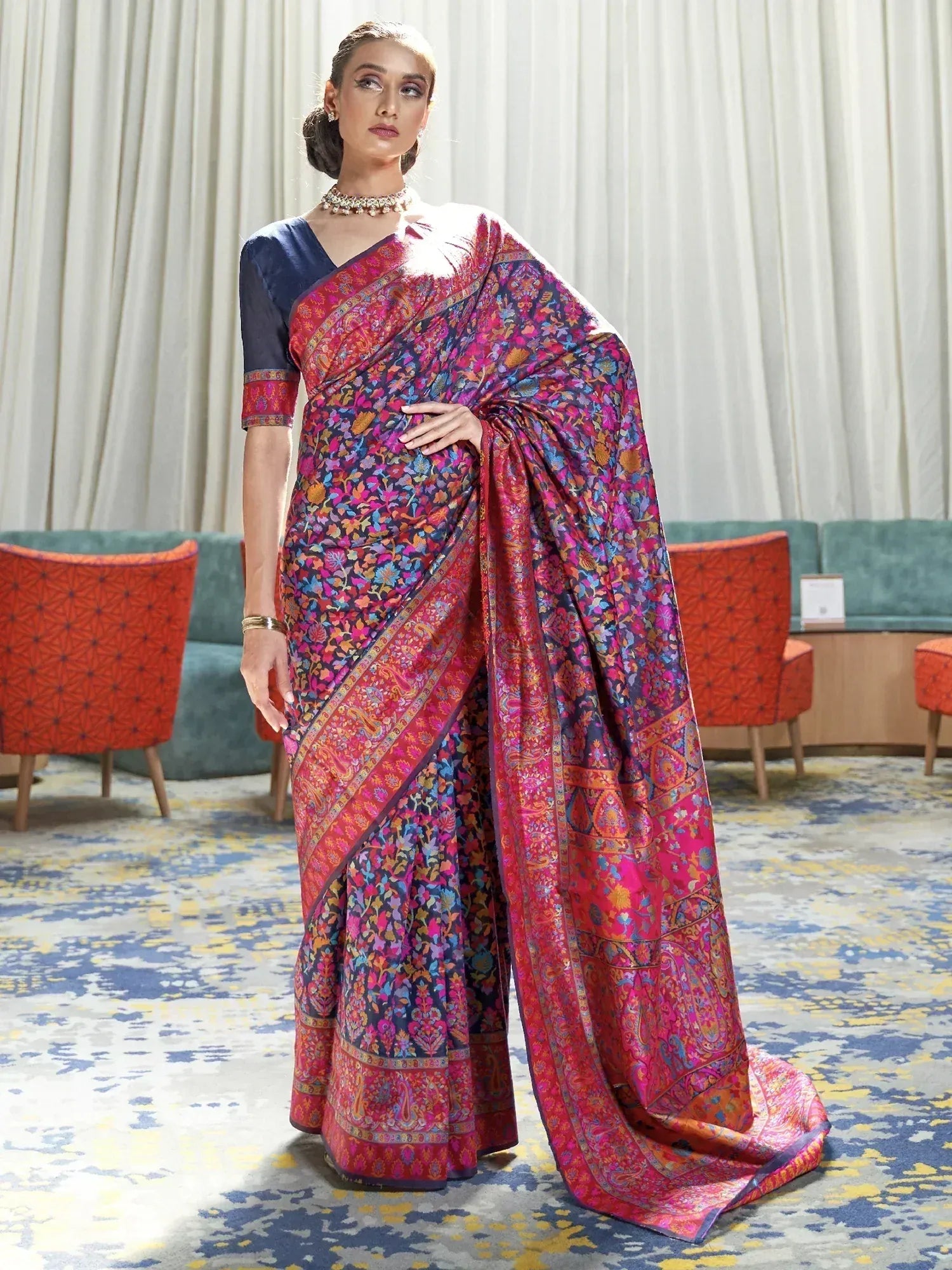 Woman in vibrant floral print saree with navy blouse, ethnic Indian wear for festive occasions