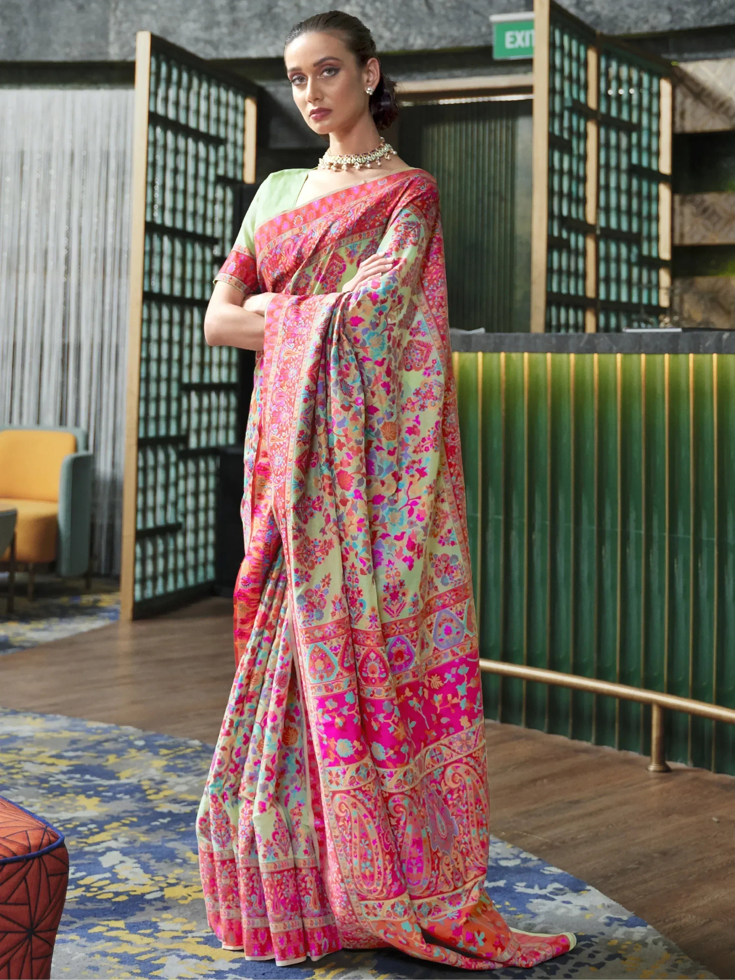 Woman in vibrant floral printed saree with pink and green hues, styled for ethnic occasions