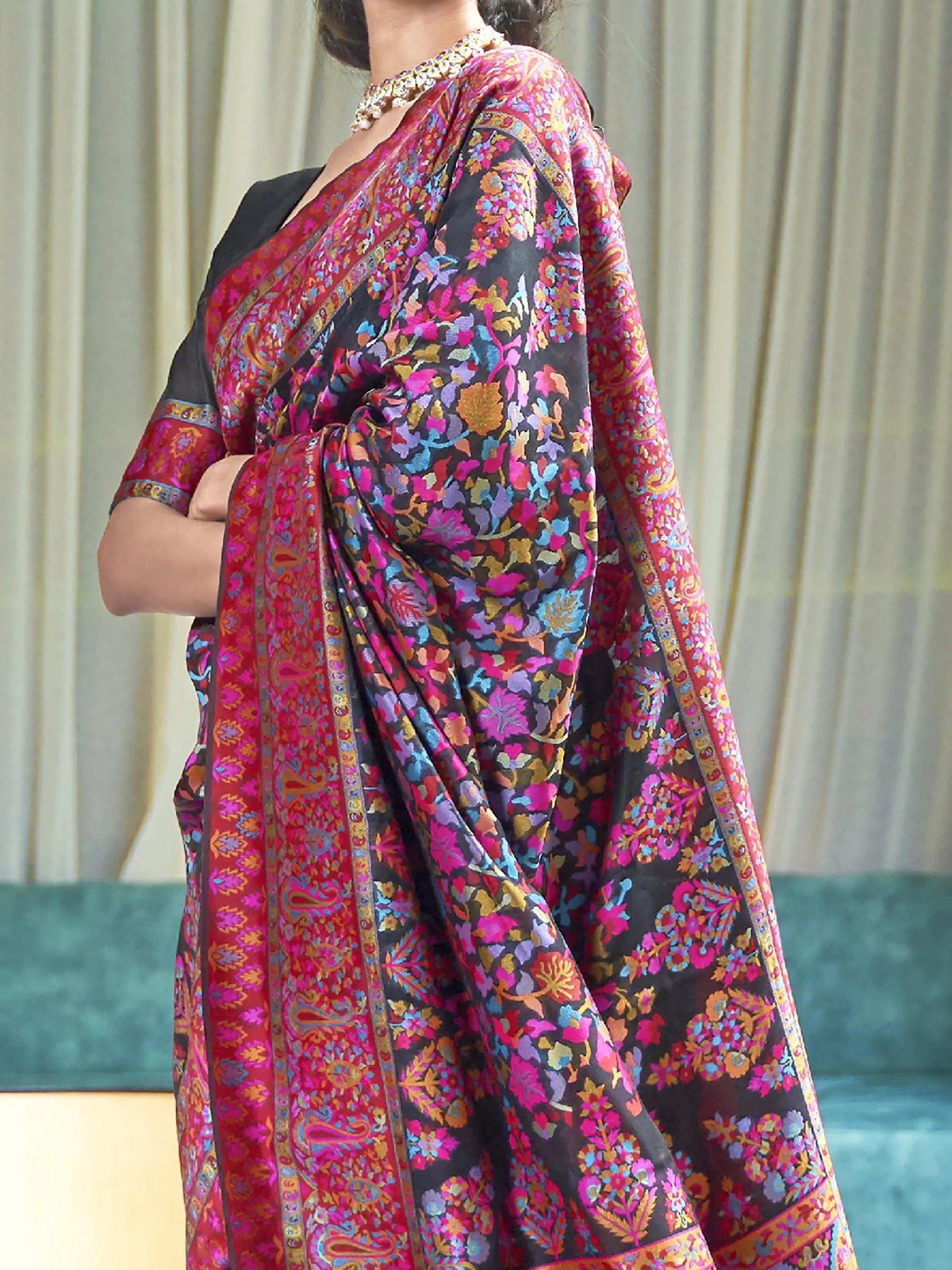 Woman in vibrant floral and paisley printed saree with contrasting border, ethnic Indian wear