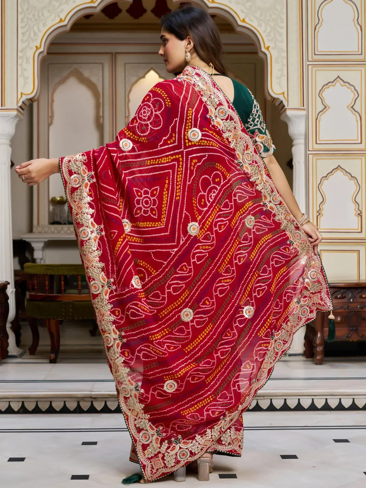 Red embroidered Indian ethnic dupatta with floral patterns, worn with green outfit in palace setting