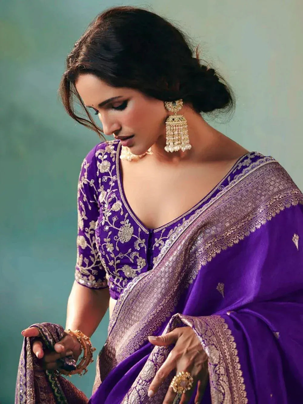 Purple embroidered saree with gold detailing and matching jewelry for ethnic wear