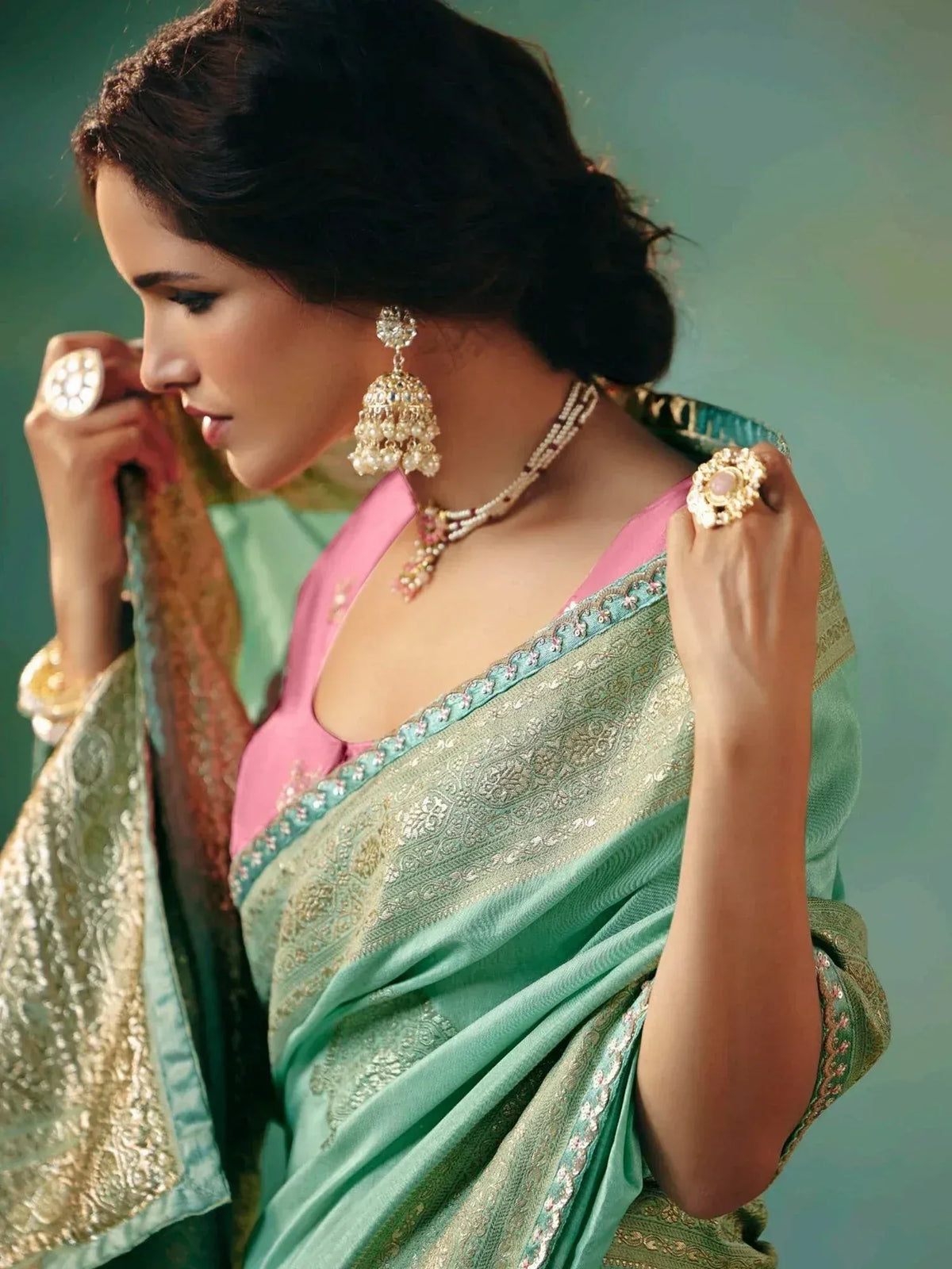 Woman in elegant mint green saree with gold embroidery, pink blouse, and traditional jewelry