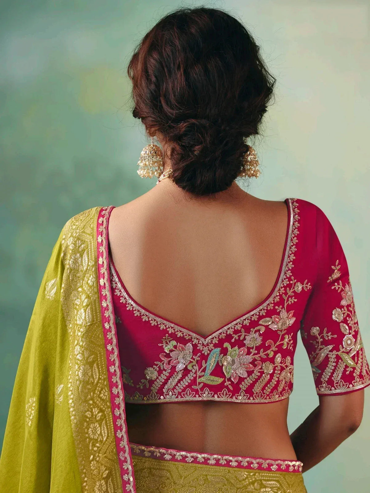 Back view of woman in red embroidered blouse with green dupatta, showcasing floral zari work and traditional Indian ethnic wear.