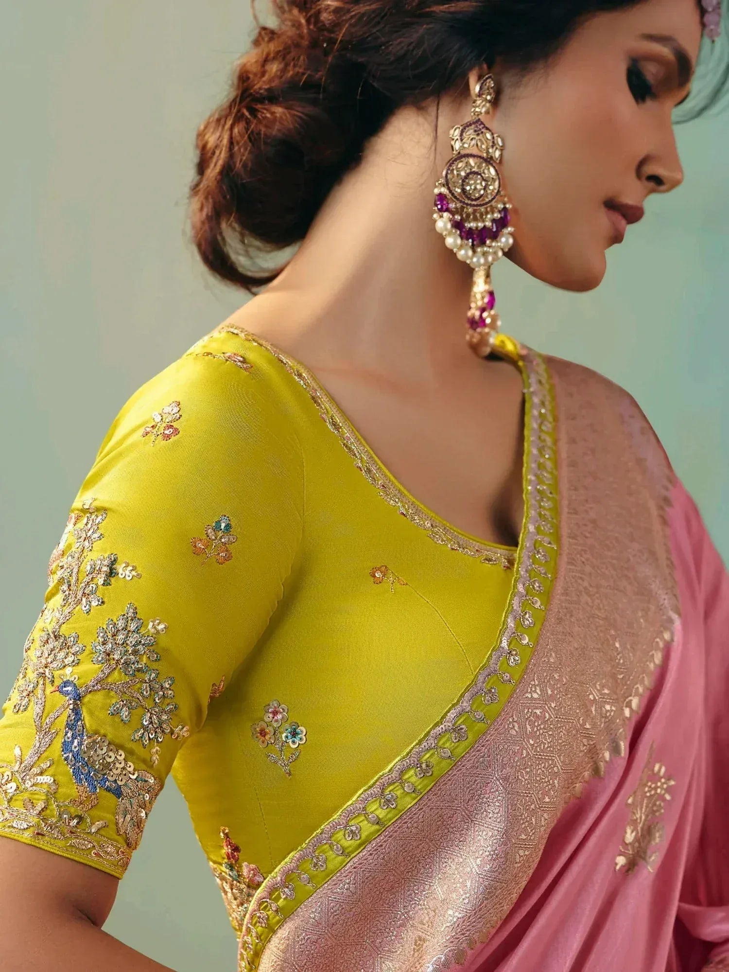 Yellow embroidered blouse with peacock design, paired with pink saree and statement earrings