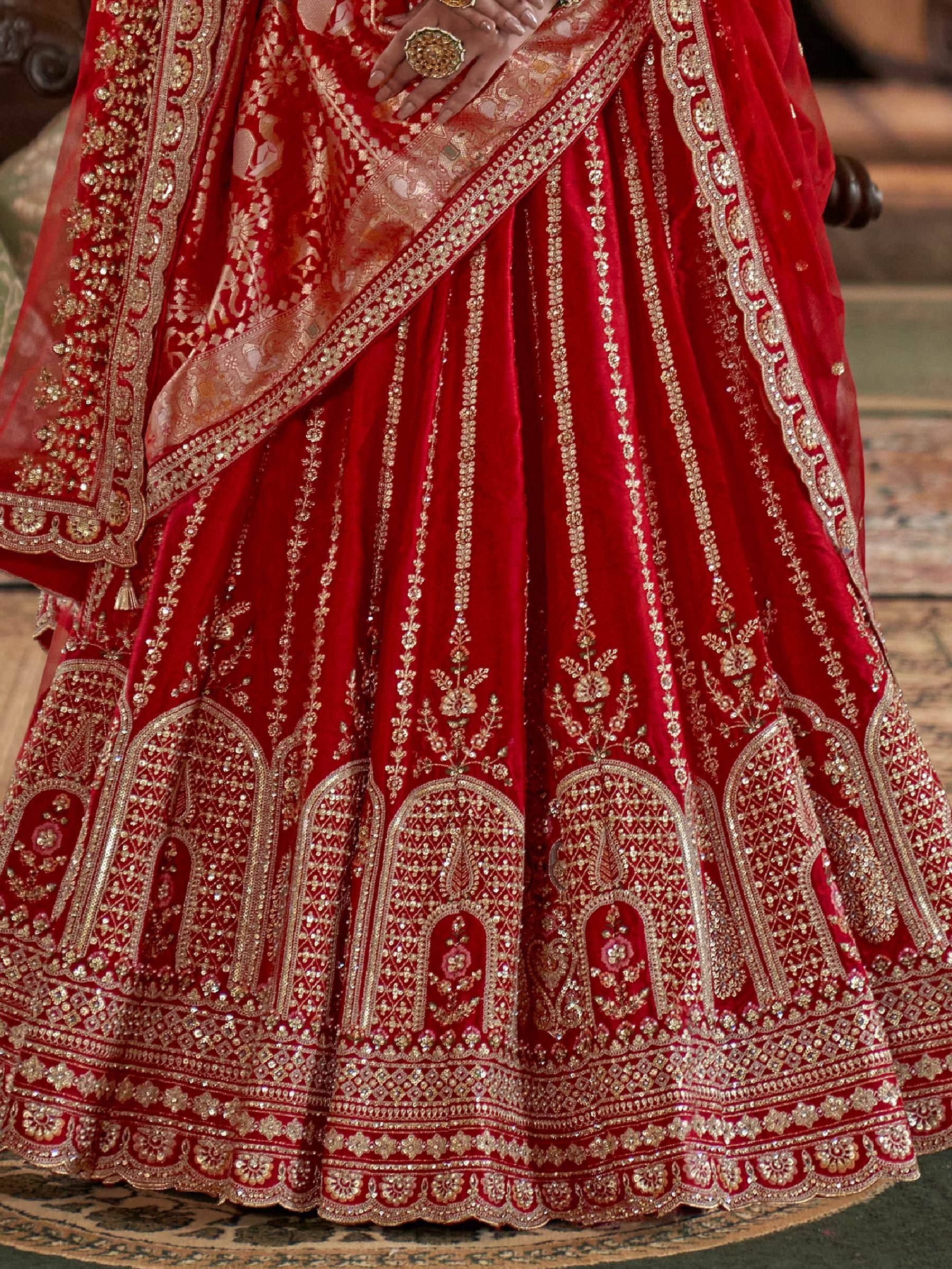 Red velvet lehenga choli with gold embroidery and embellished dupatta, perfect for Indian weddings and festive occasions.