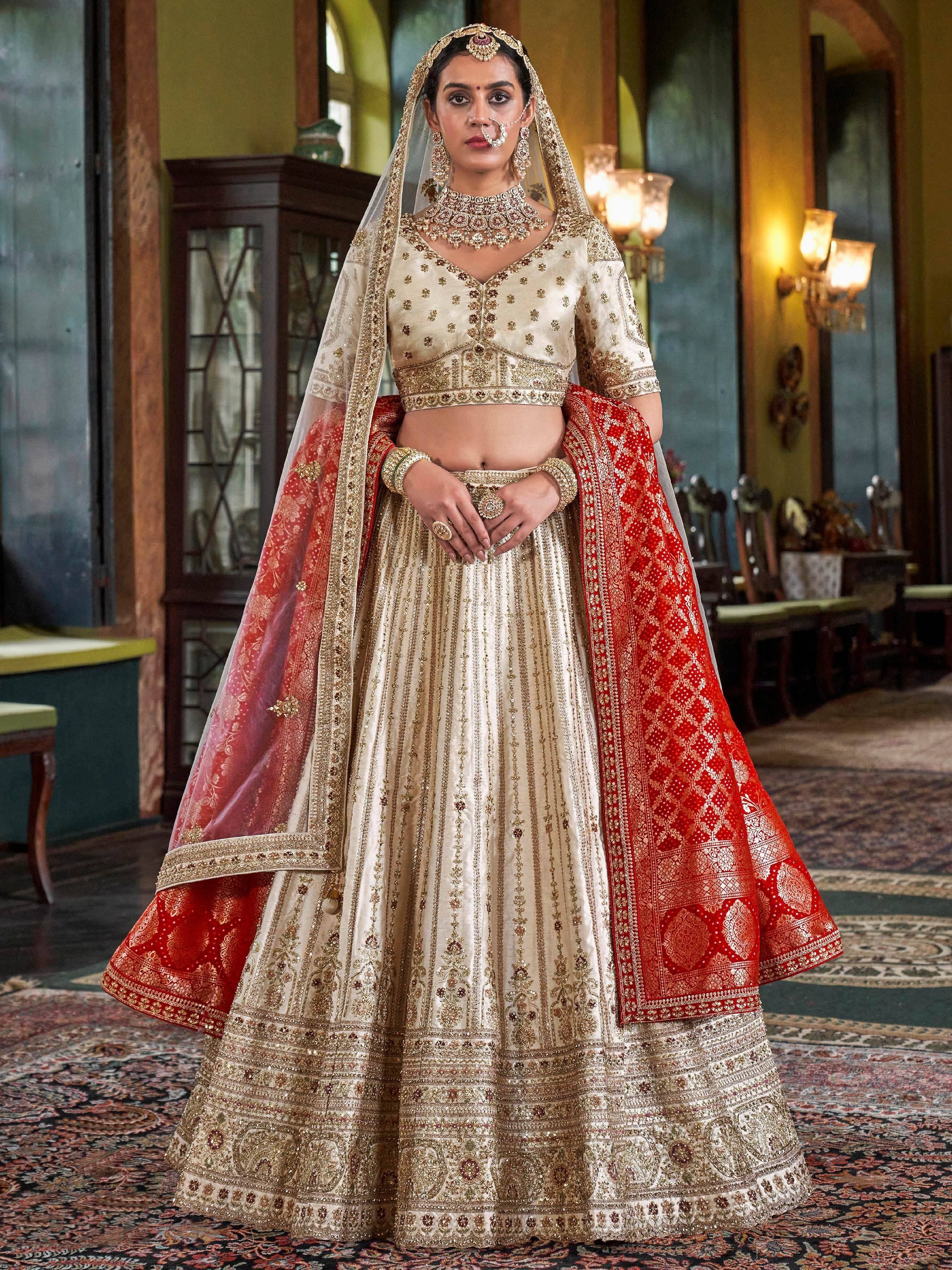 Cream and red designer lehenga choli with gold embroidery, perfect for Indian weddings and ethnic events.