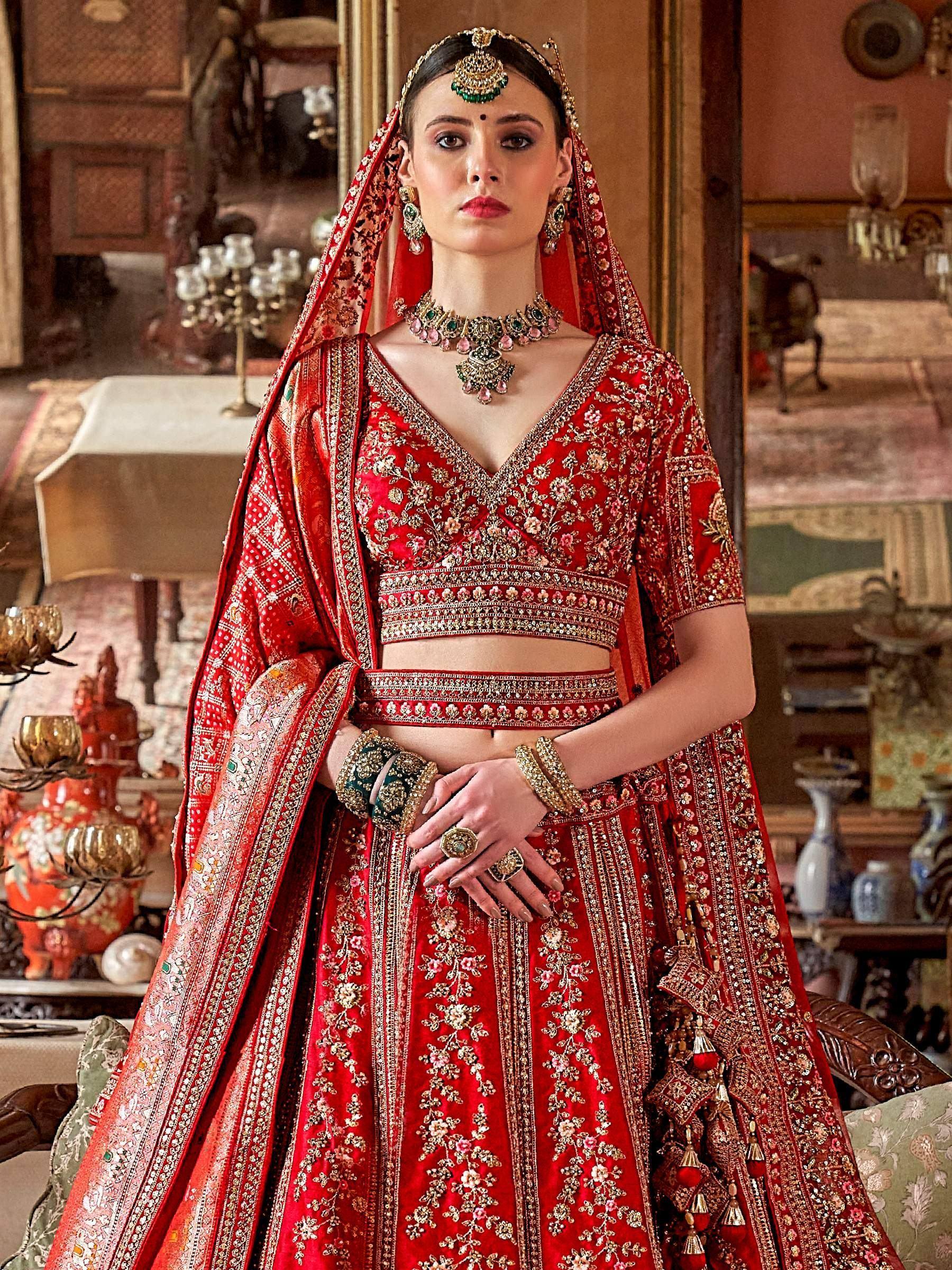 Red embroidered lehenga choli with heavy jewelry, perfect for Indian weddings and ethnic occasions.