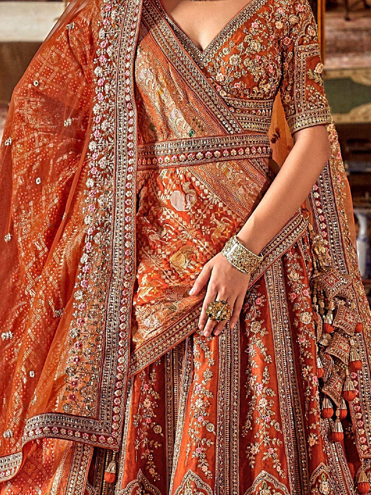 Orange embroidered lehenga choli with floral motifs and tassels, perfect for Indian weddings and festive occasions