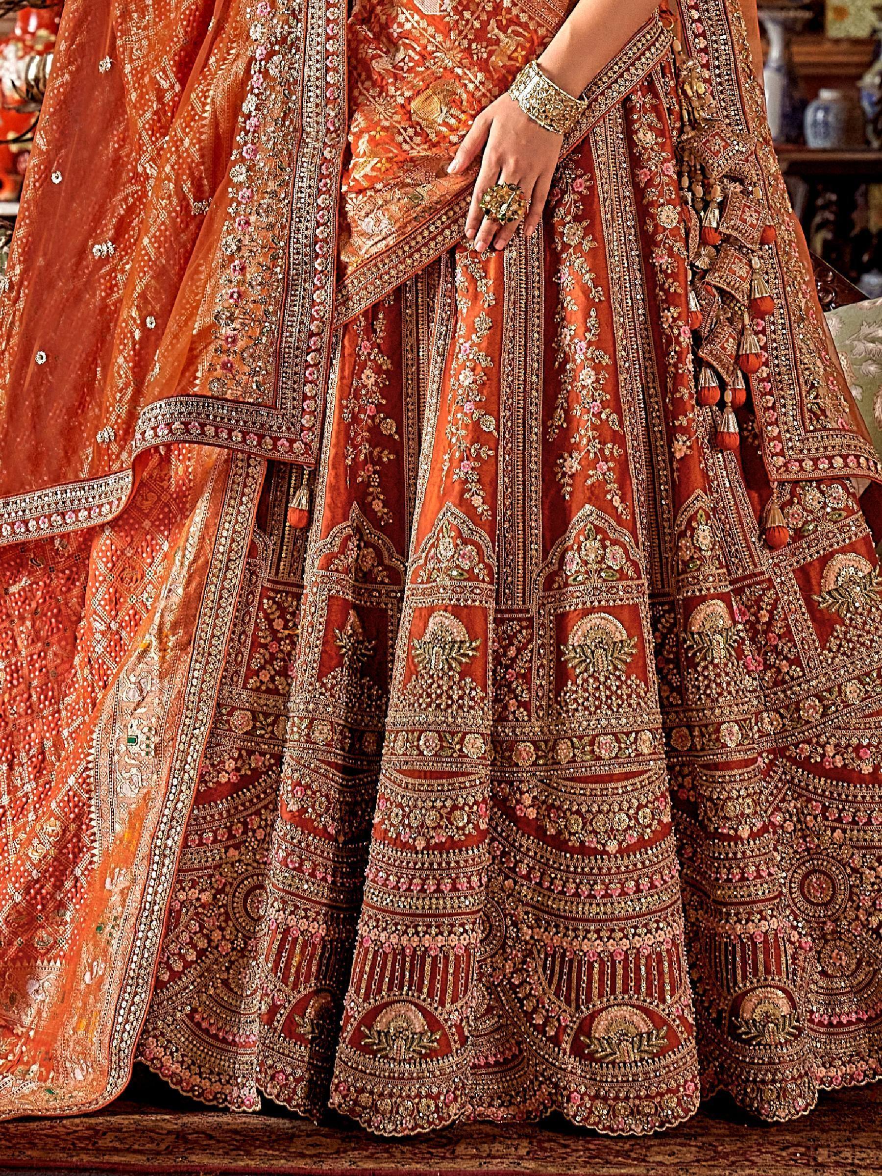 Luxury orange bridal lehenga with heavy gold embroidery and floral motifs, perfect for Indian weddings.