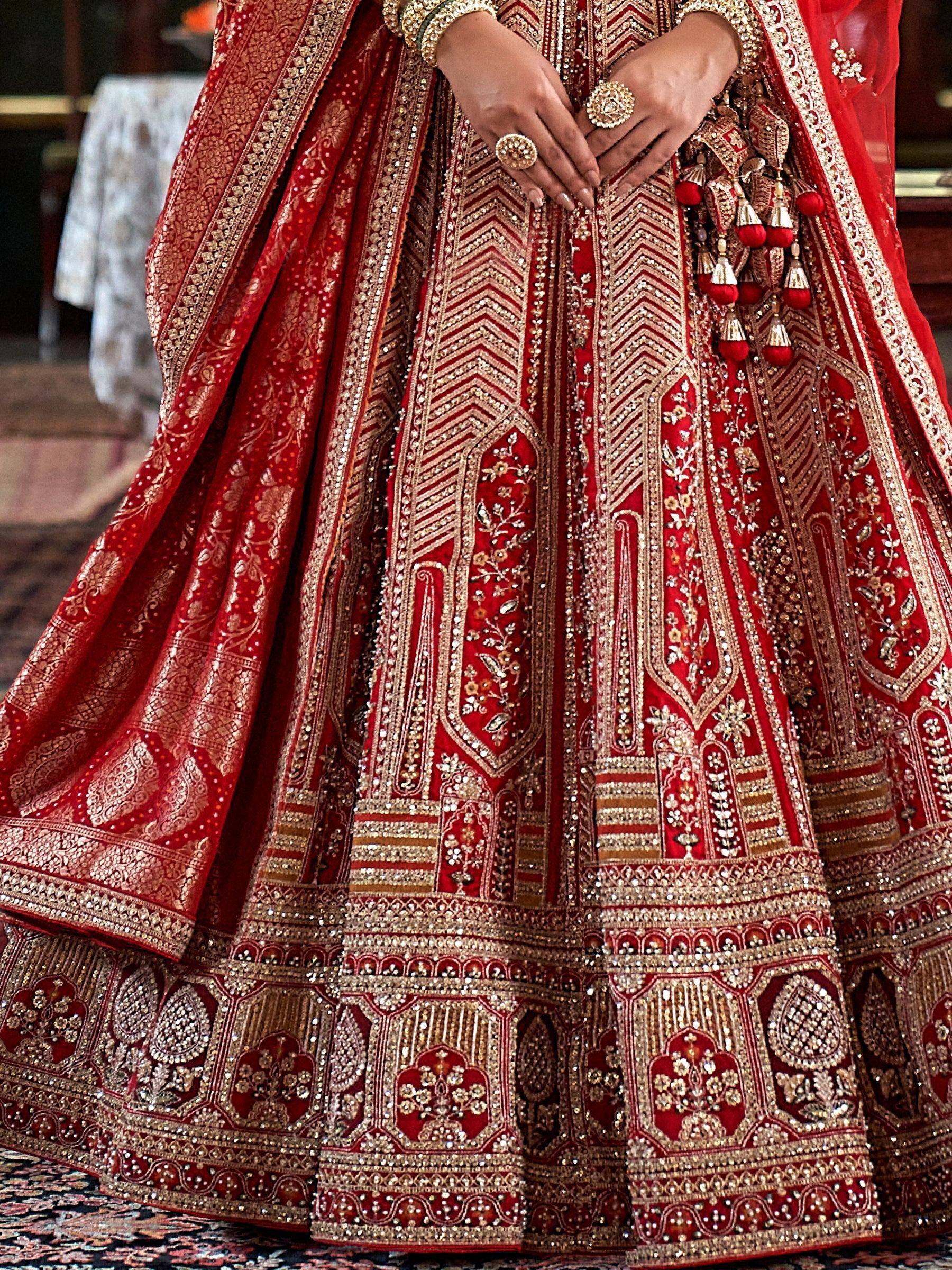 Red and gold embroidered bridal lehenga with intricate zari work and tassels, perfect for Indian weddings.