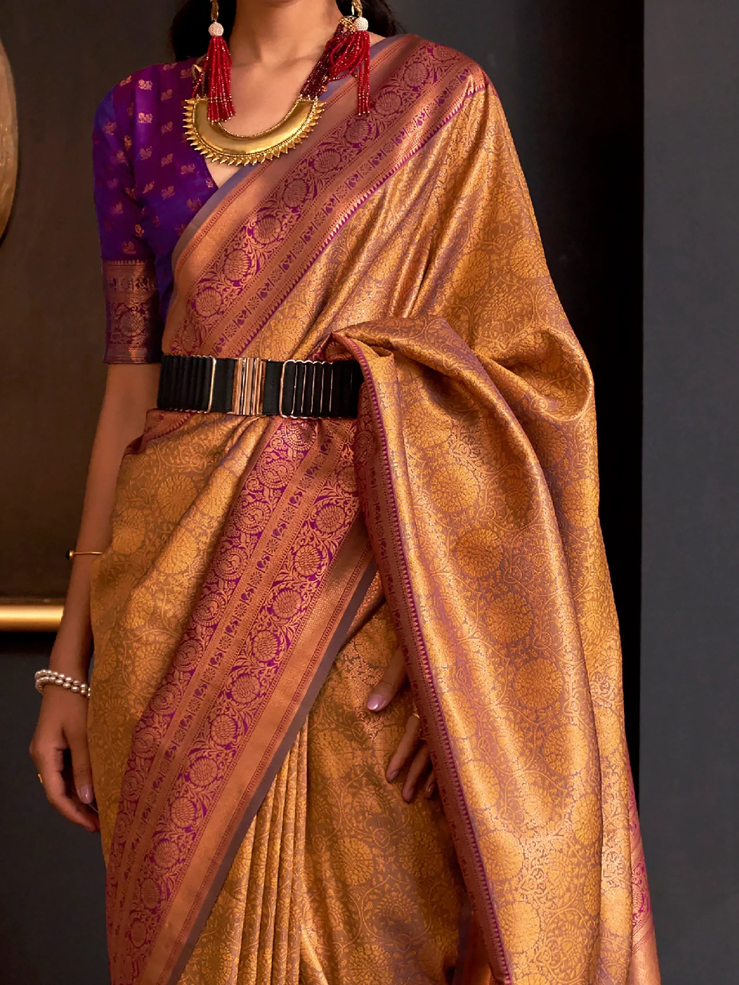 Golden brocade saree with purple border, paired with matching blouse and statement jewelry for ethnic wear