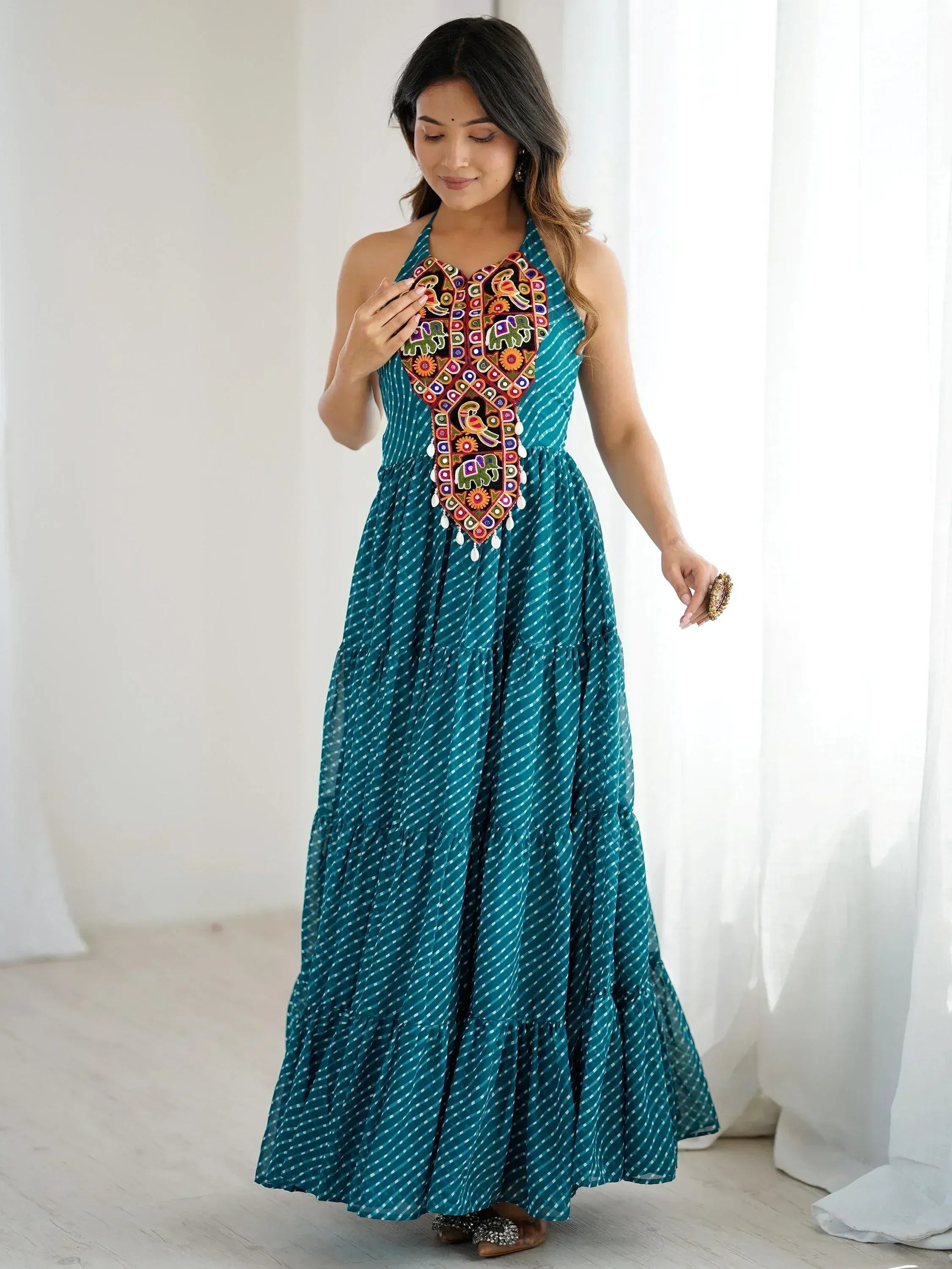 Teal ethnic gown with colorful embroidery and tiered skirt, perfect for Indian festive occasions.