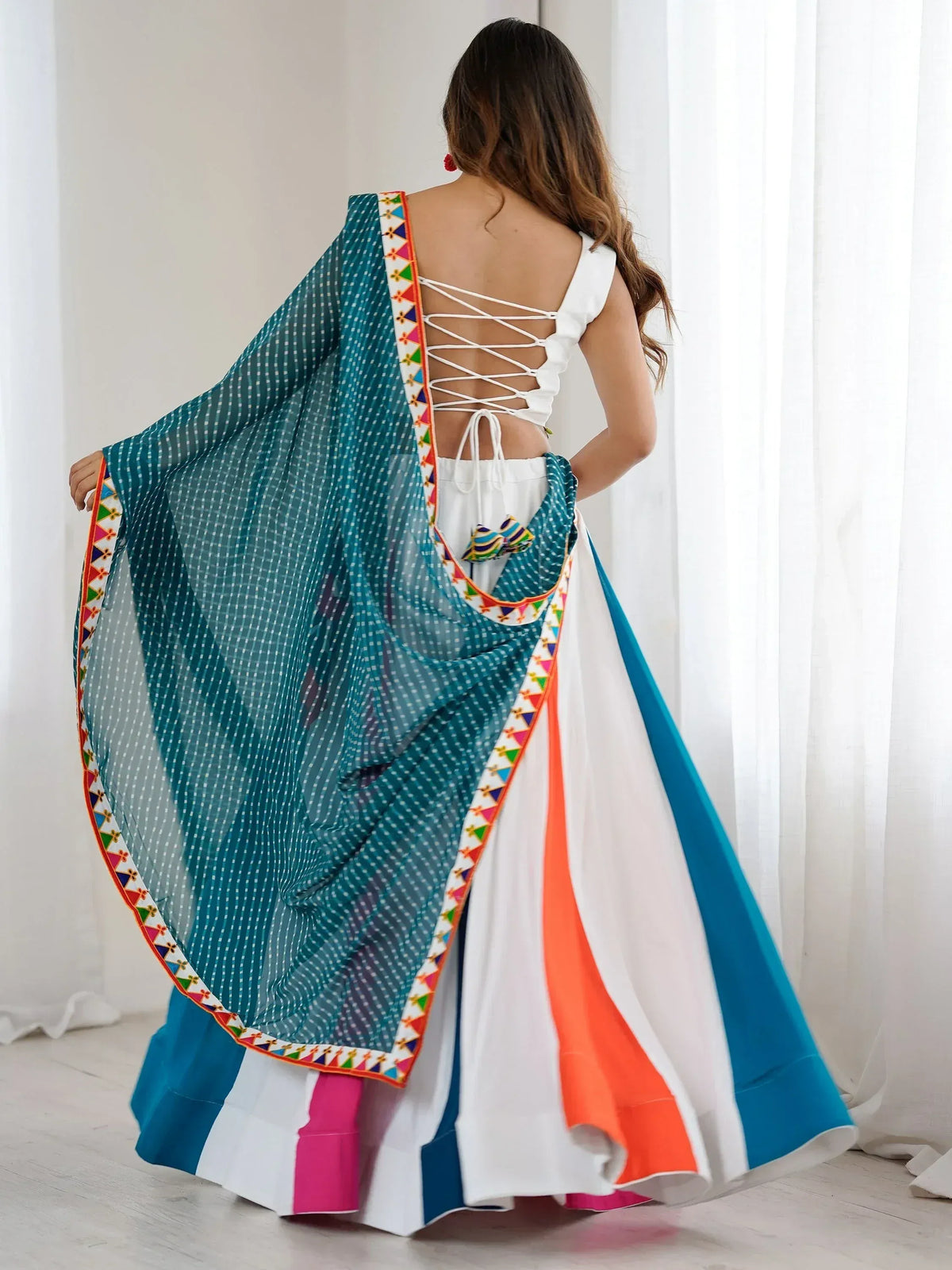 Woman in colorful ethnic lehenga choli with backless top and embroidered dupatta, perfect for festive occasions.